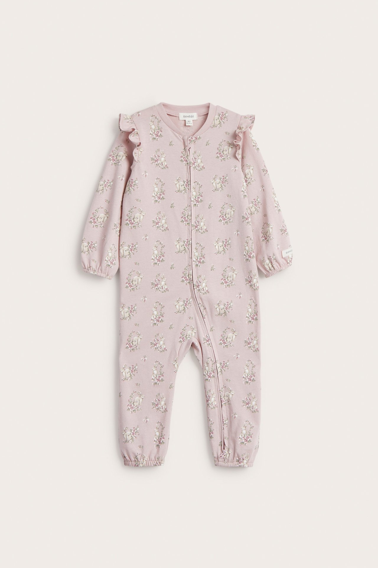 Edestä: Vaaleanpunainen puuvillapyjama, kukkaisella kaninprintillä, olkarypytyksillä, kaksisuuntaisella vetoketjulla.