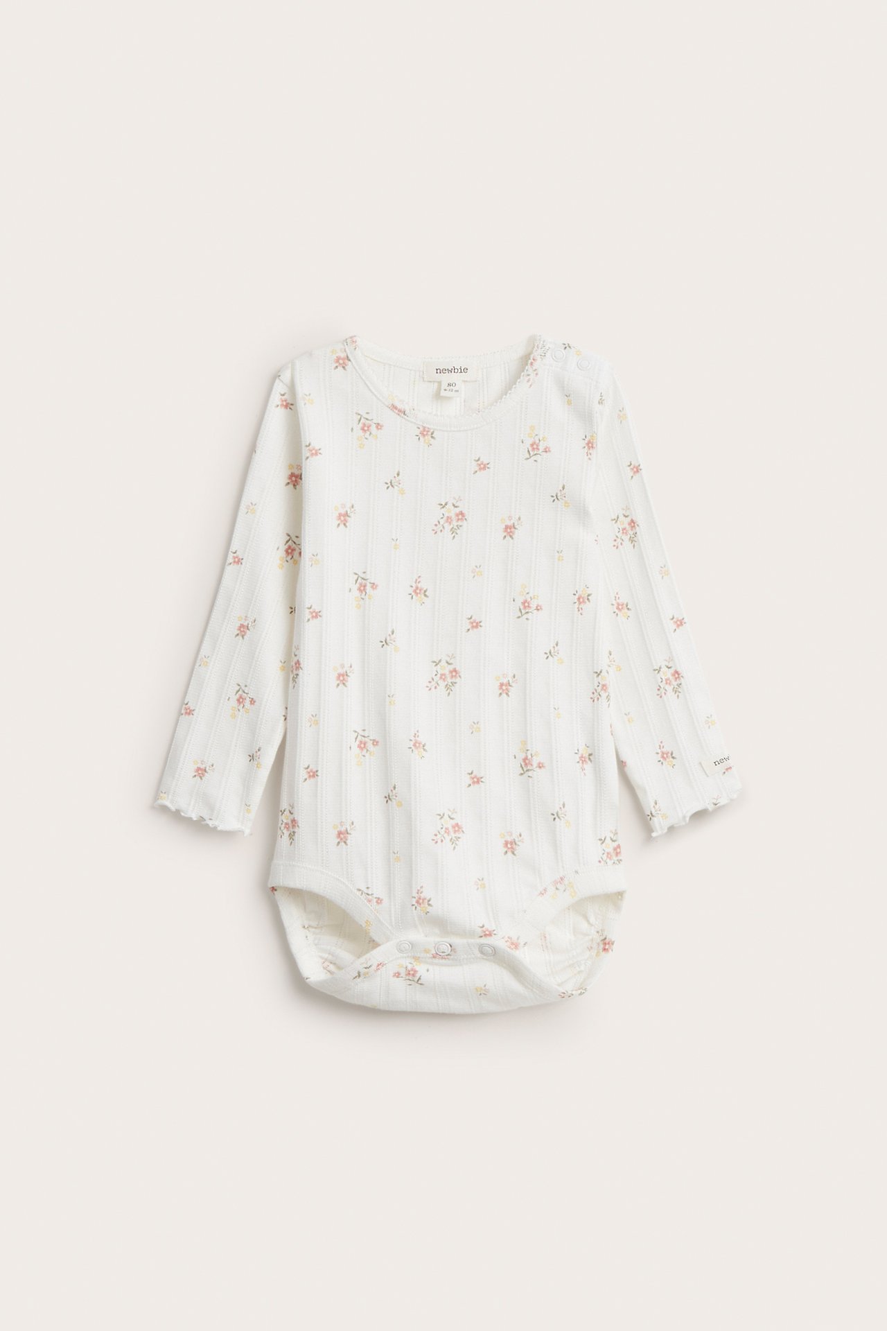 Frontvisning: Offwhite langermet babybody i pointelle ribb med blomstertrykk og trykknapper.