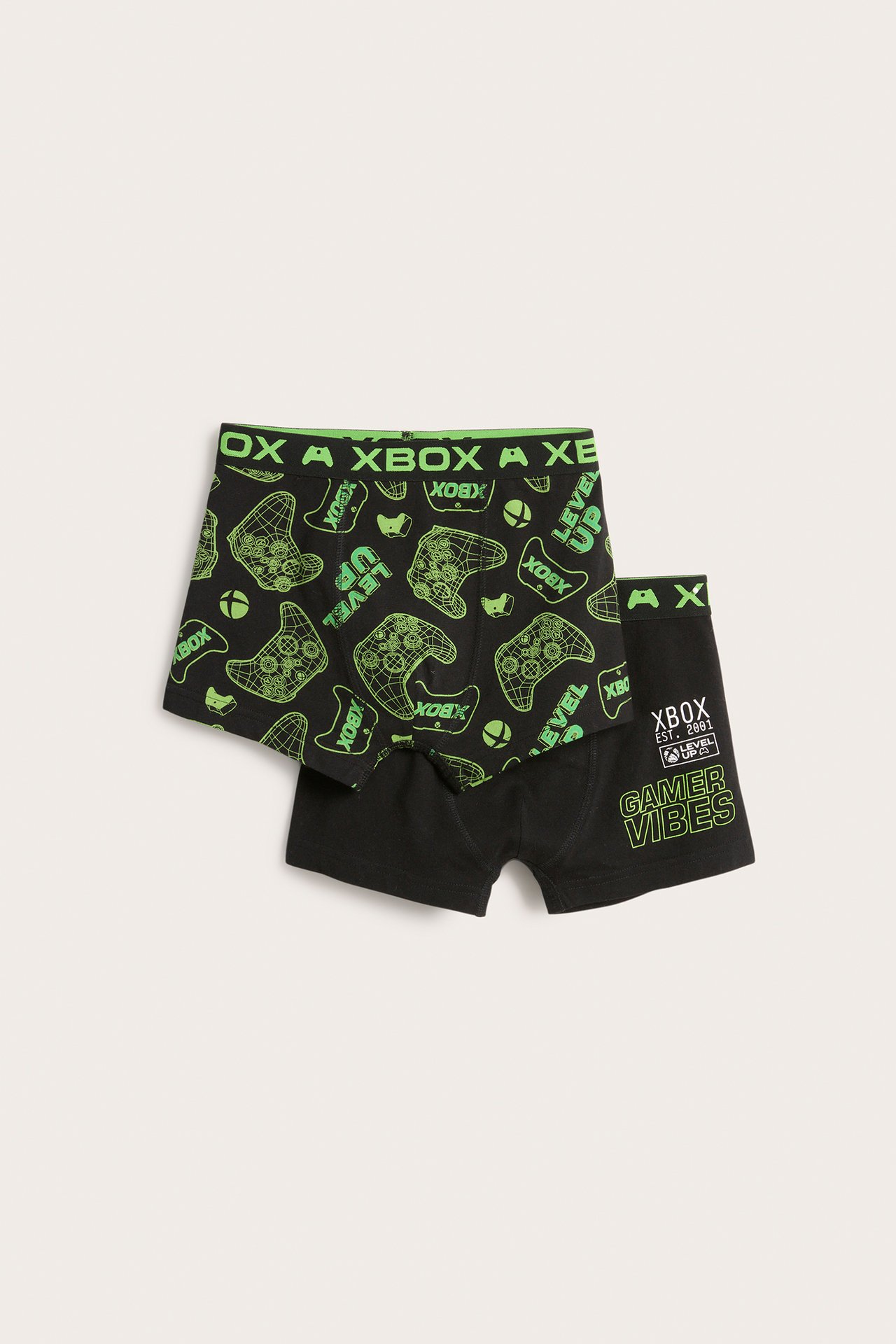 Edestä näkymä kahdesta lasten mustasta puuvillaisesta Xbox-bokserista. Toisessa vihreä ohjainkuvio, toisessa vihreä tekstipainatus.