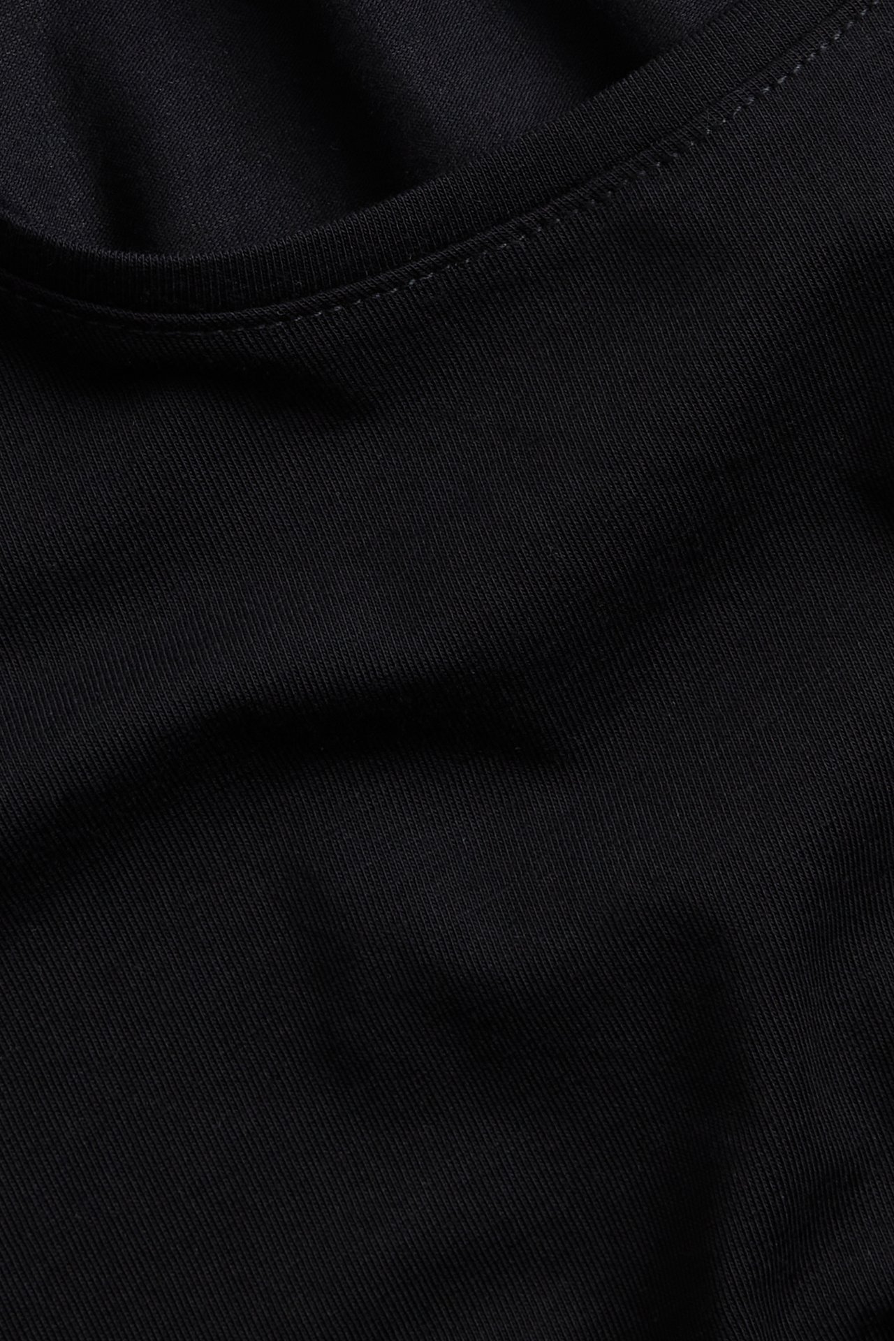 Zbliżenie czarnego, jednolitego t-shirtu z krótkim rękawem i okrągłym dekoltem, z mieszanki bawełny.