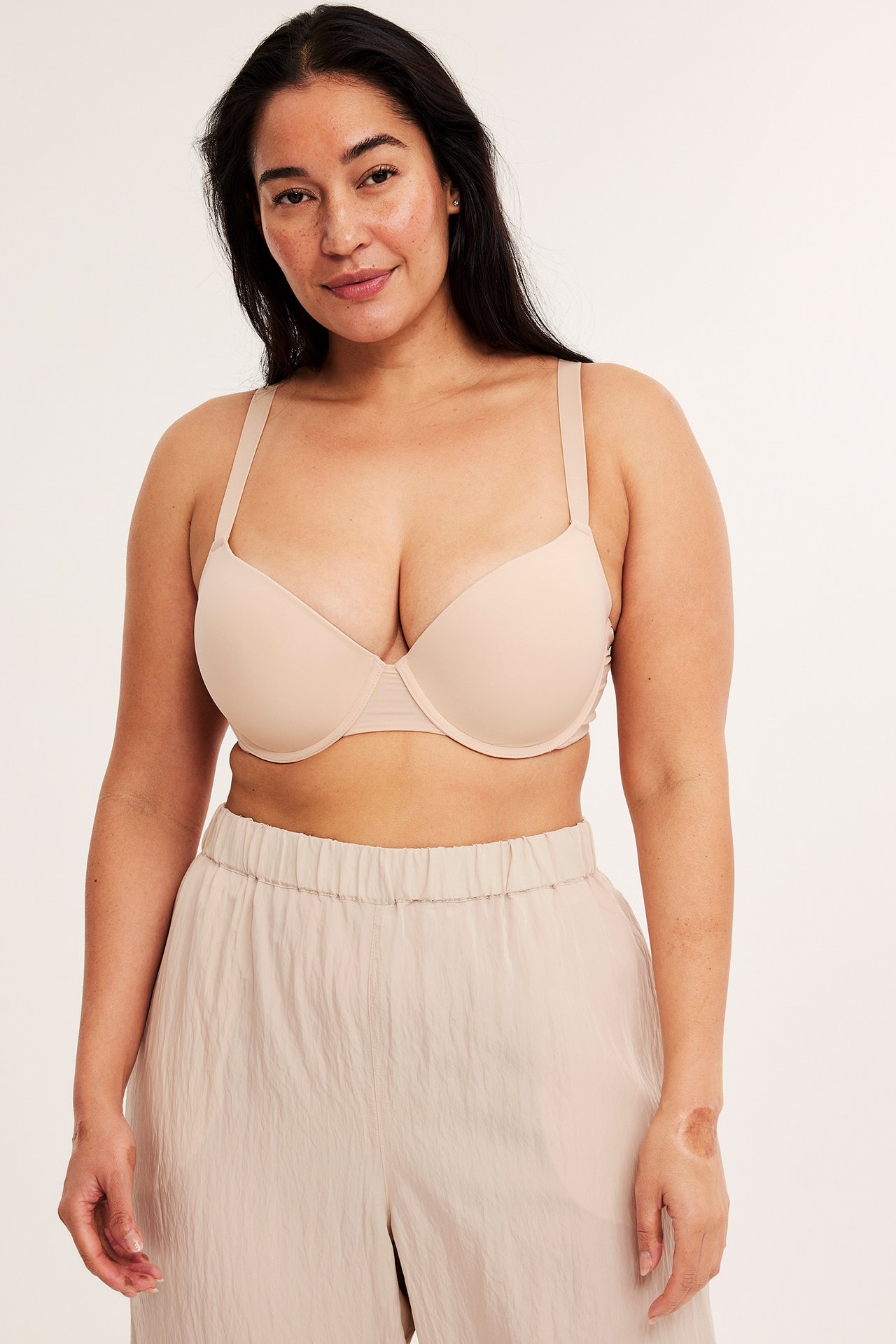 Forfra: kvinne i lys beige push-up-BH med justerbare stropper og lys beige vide bukser.