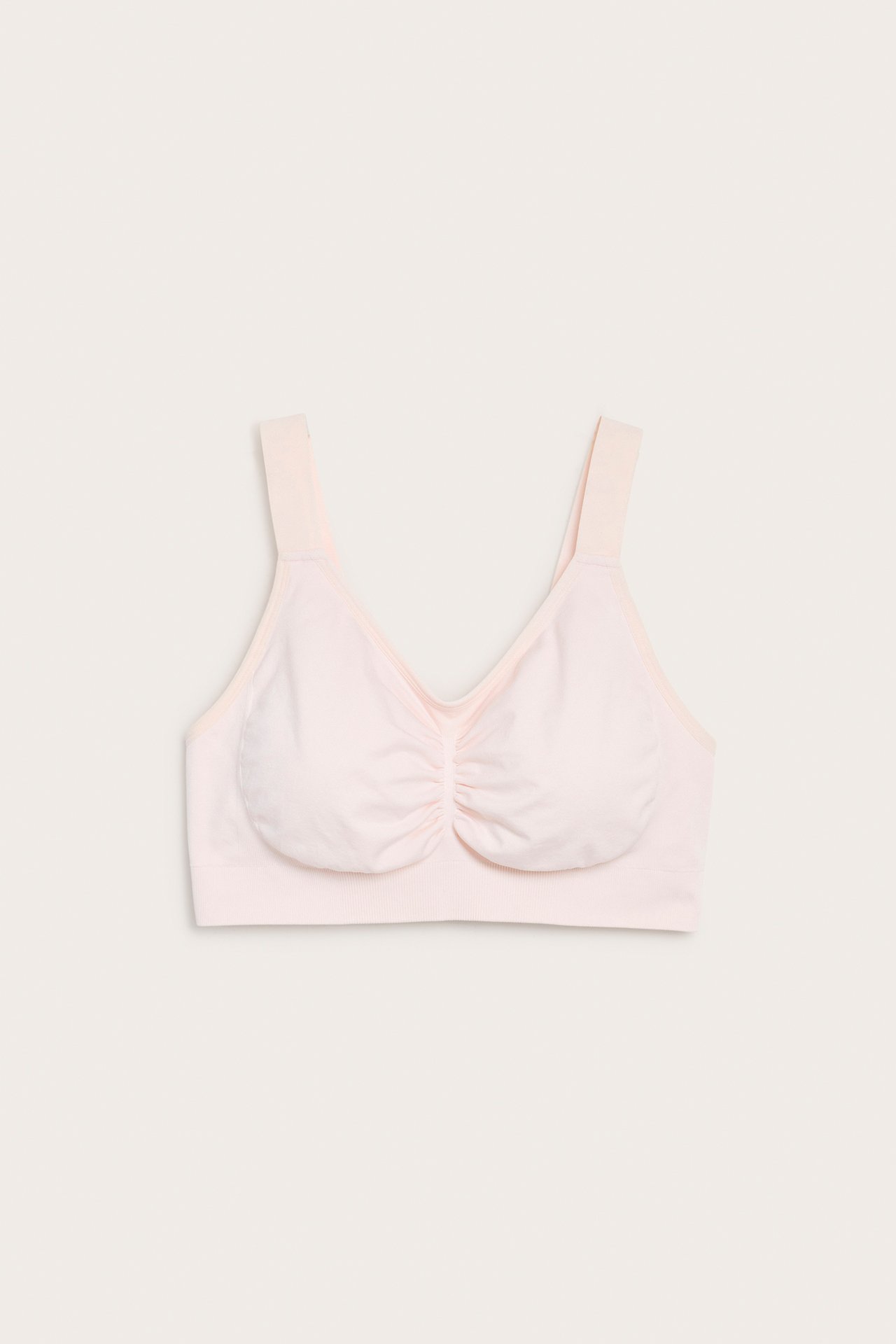 Framifrån, rosa sömlös bygellös bh med löstagbar vaddering och rynkad mitt.