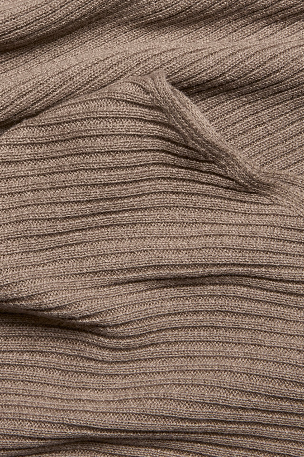 Nærbilde av mørk beige ribbestrikket genserstoff, som viser dets strukturerte mønster.