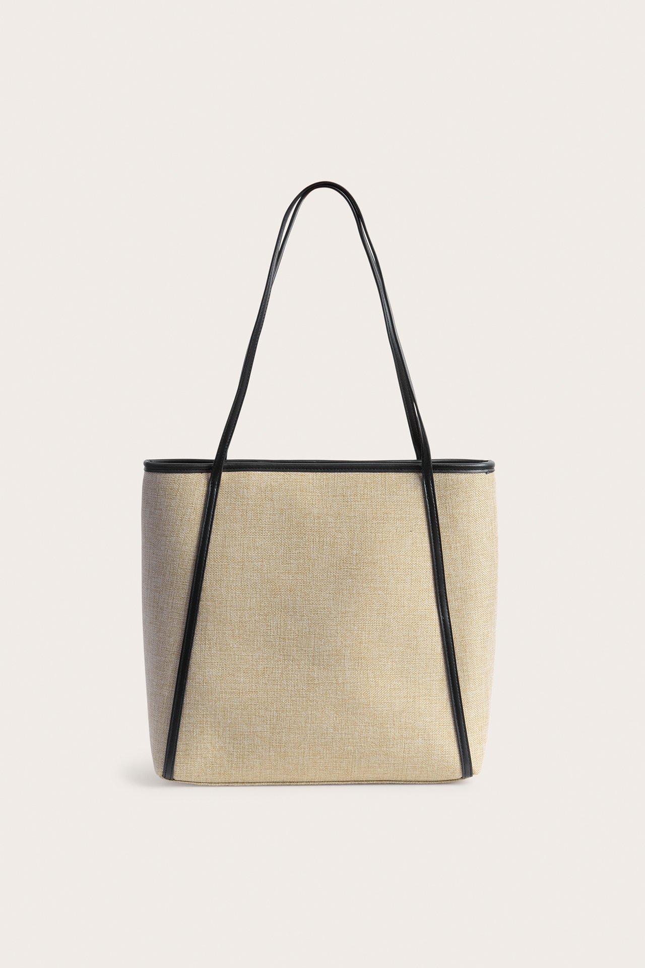 Frontvy av en beige strå-look tygväska med svarta handtag och kant i läderimitation.