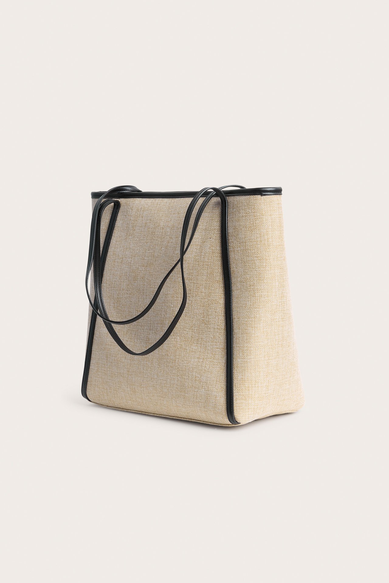 Beige stråliknande totebag med svarta handtag och kant i läderimitation, framifrån/sida.