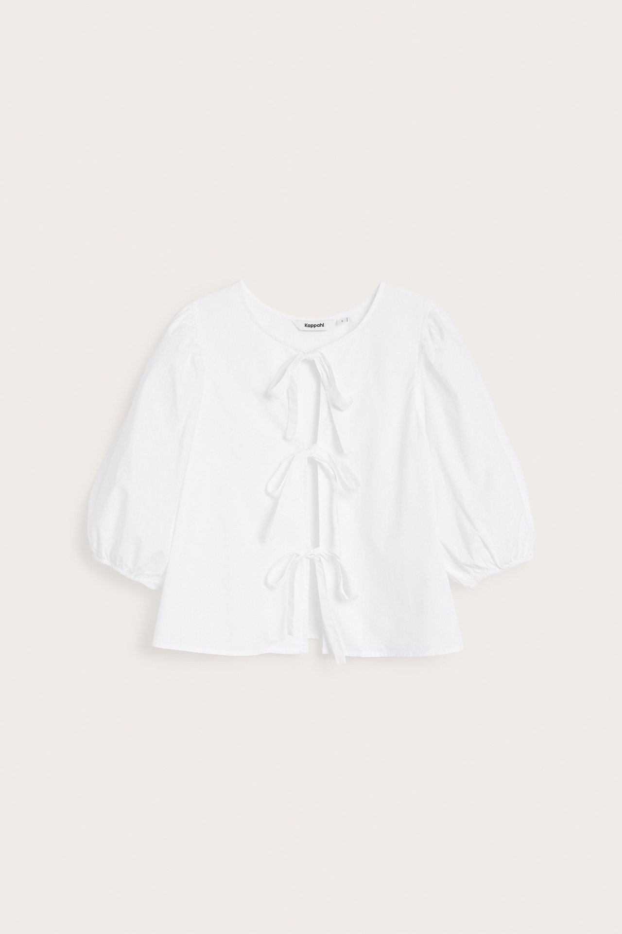 Widok z przodu białej bawełnianej bluzki z bufiastymi rękawami i trzema wiązaniami z przodu.