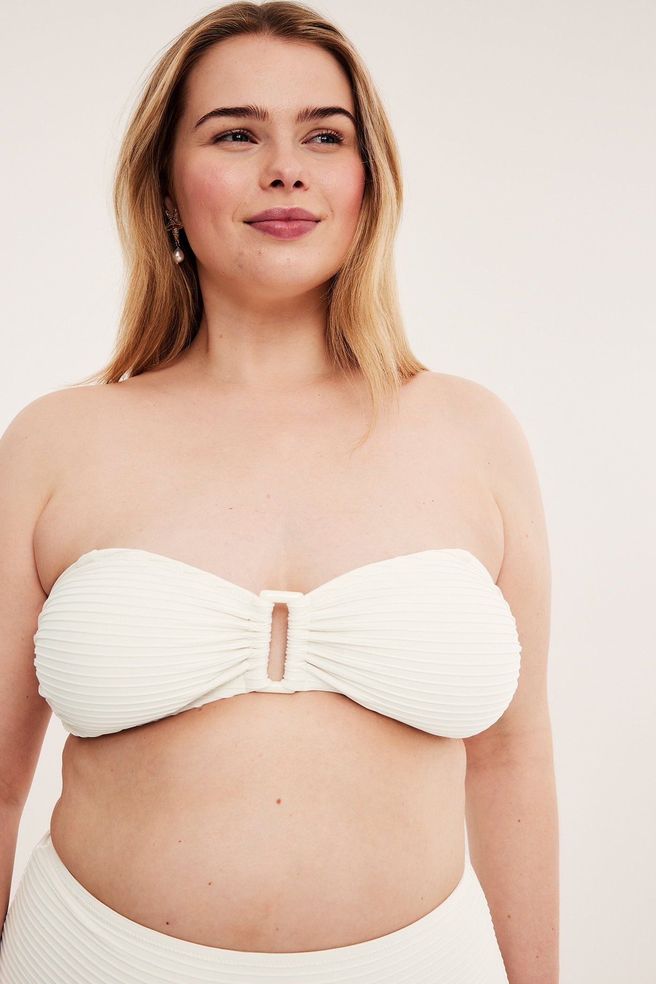Forfra: kvinne i offwhite strukturert bandeau-bikinitopp med spenne foran og matchende underdel.