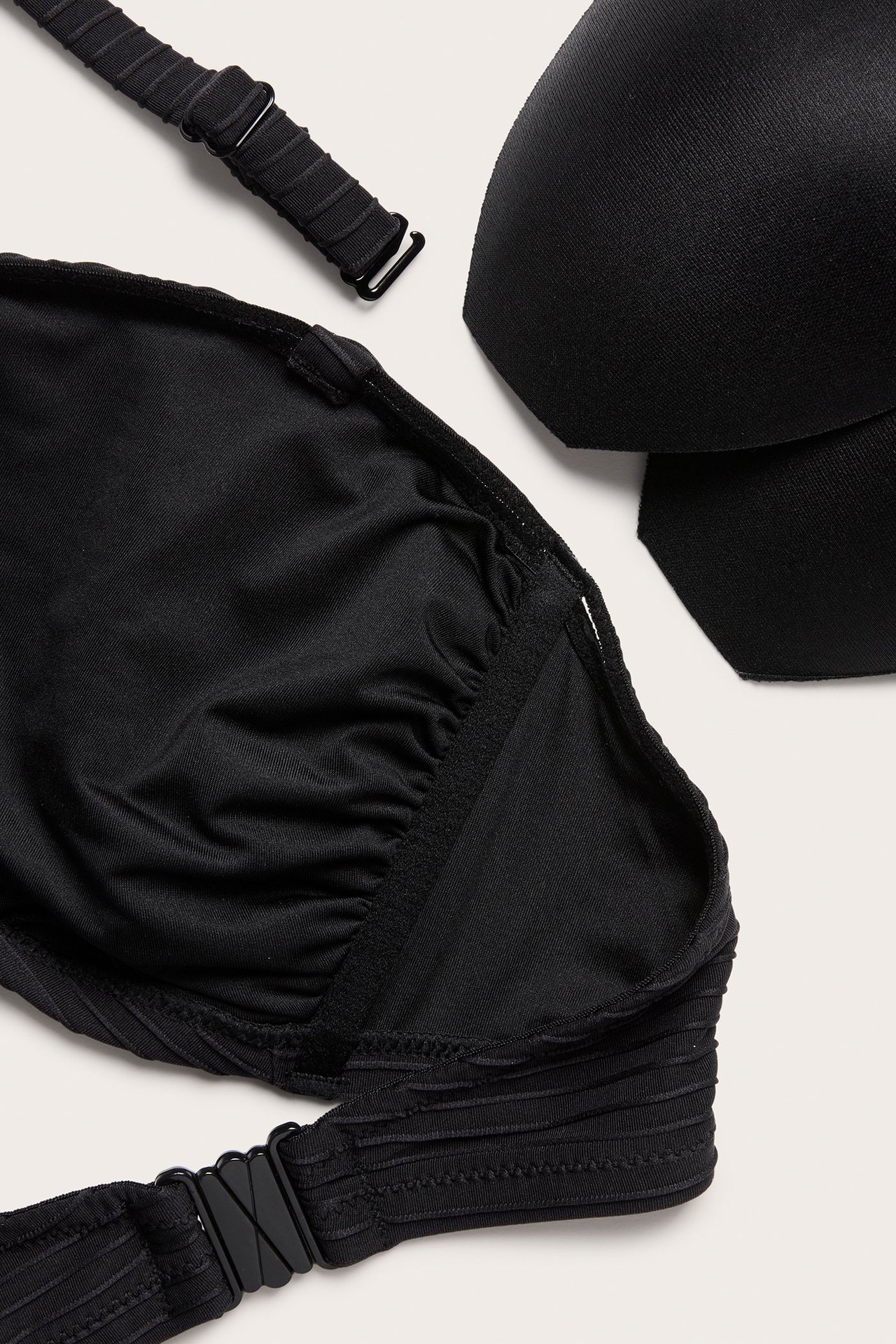 Zbliżenie czarnego, teksturowanego biustonosza bikini bandeau z ramiączkiem i wyjmowanymi wkładkami.