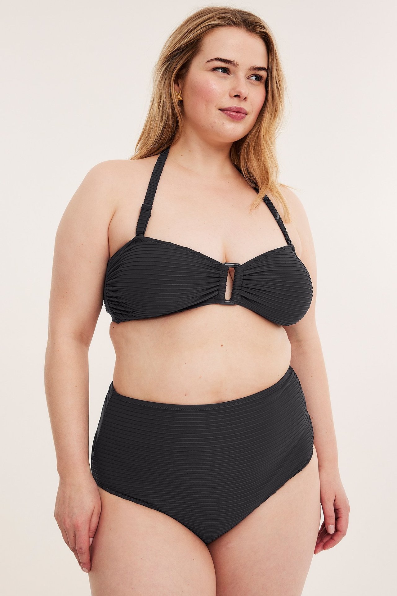 Widok z przodu: Kobieta w czarnym teksturowanym biustonoszu bandeau z klamrą i pasujących majtkach z wysokim stanem.
