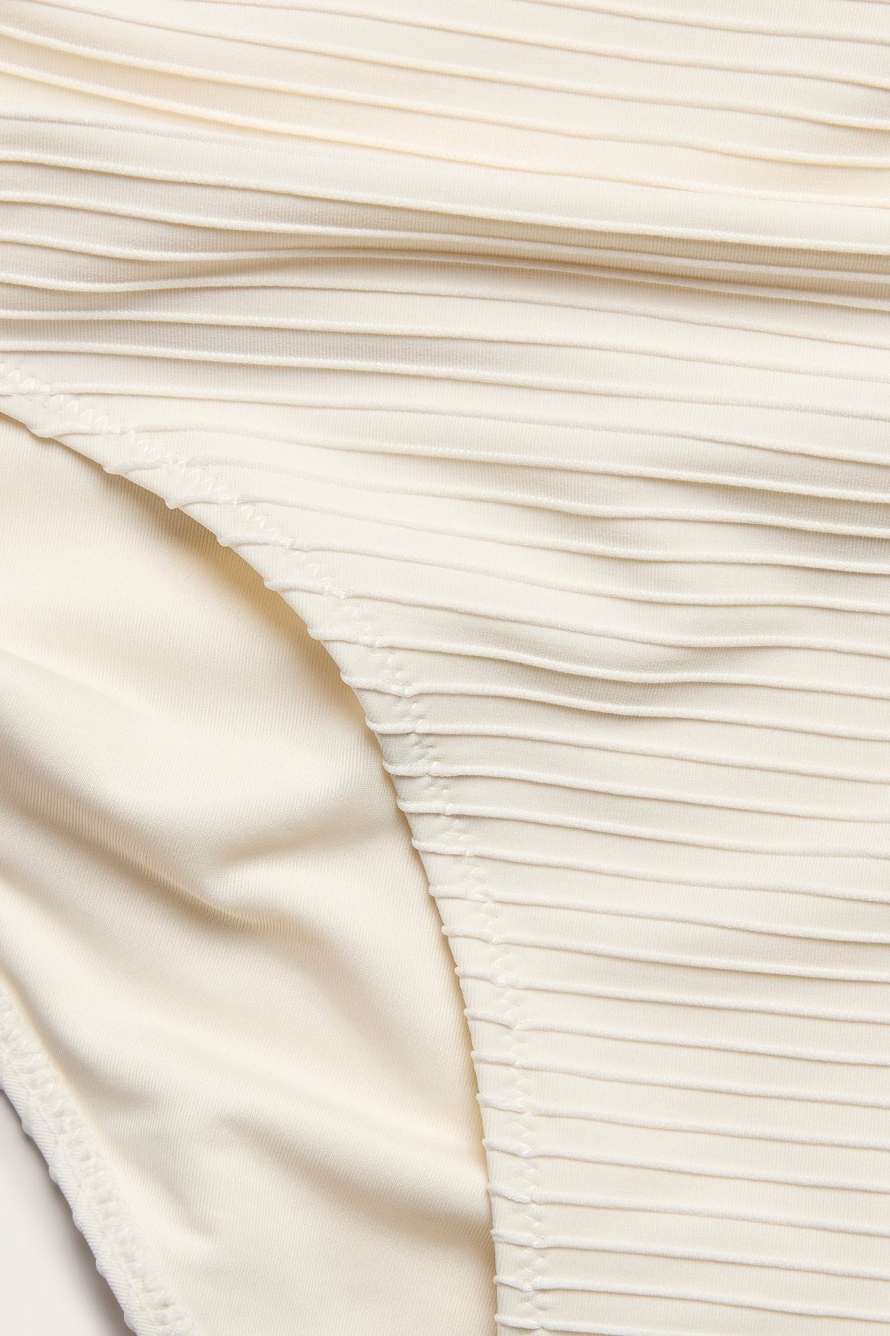 Zbliżenie na kremowe, wysokie figi bikini z teksturowaną powierzchnią.