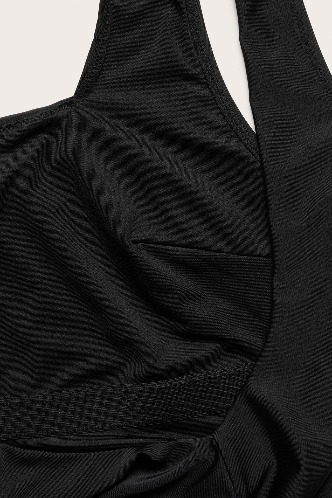 Zbliżenie czarnego jednobarwnego kostiumu kąpielowego z gładkiego materiału z elastyczną taśmą.