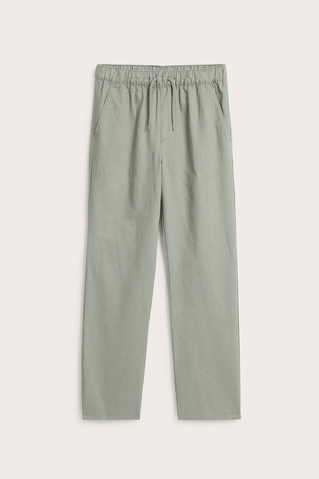 Widok z przodu zielonych spodni dziecięcych z lnu, z elastyczną talią, sznurkiem i kieszeniami.