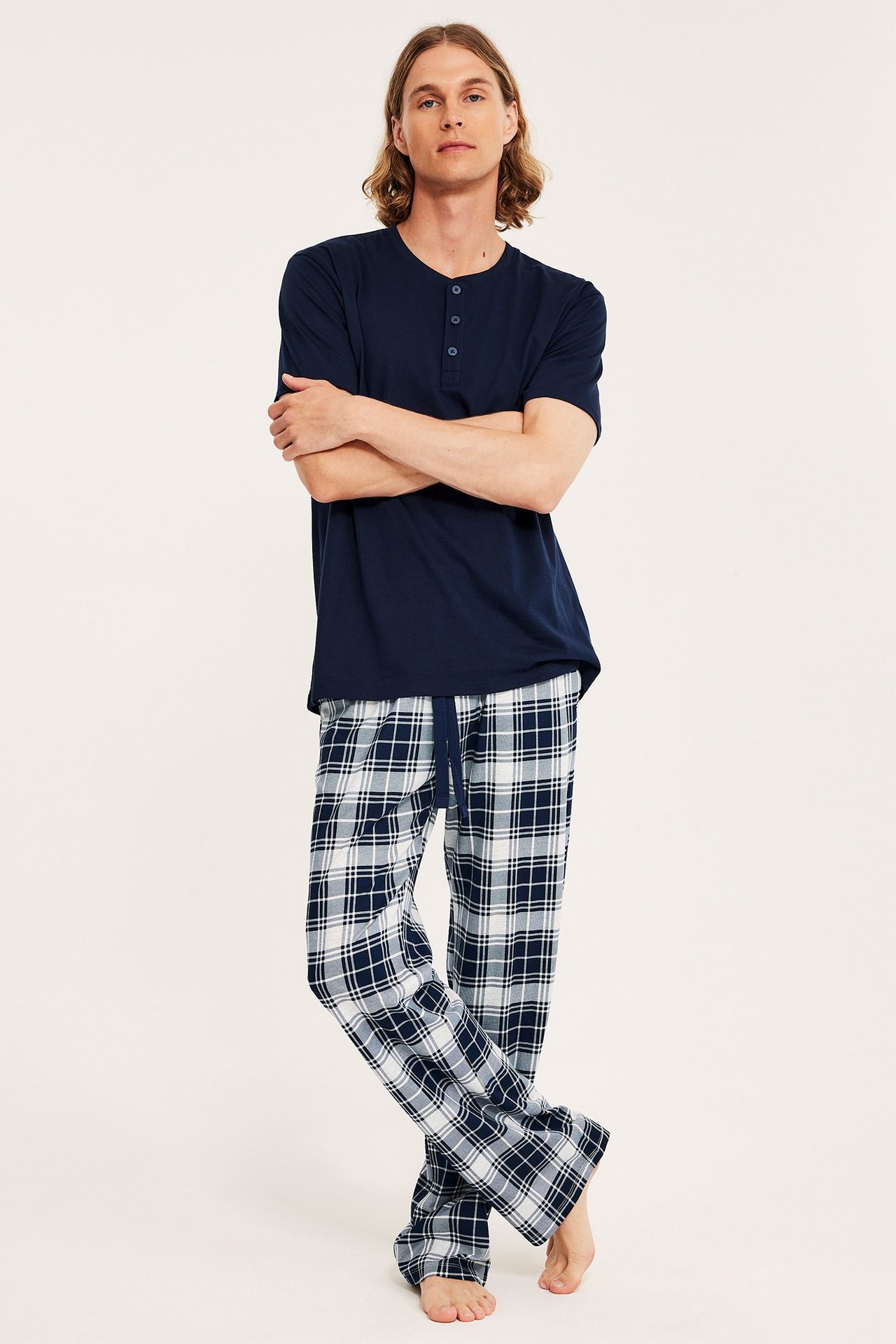 Edestä: mies tummansinisissä ja valkoruutuisissa pyjamahousuissa ja laivastonsinisessä henley-paidassa.