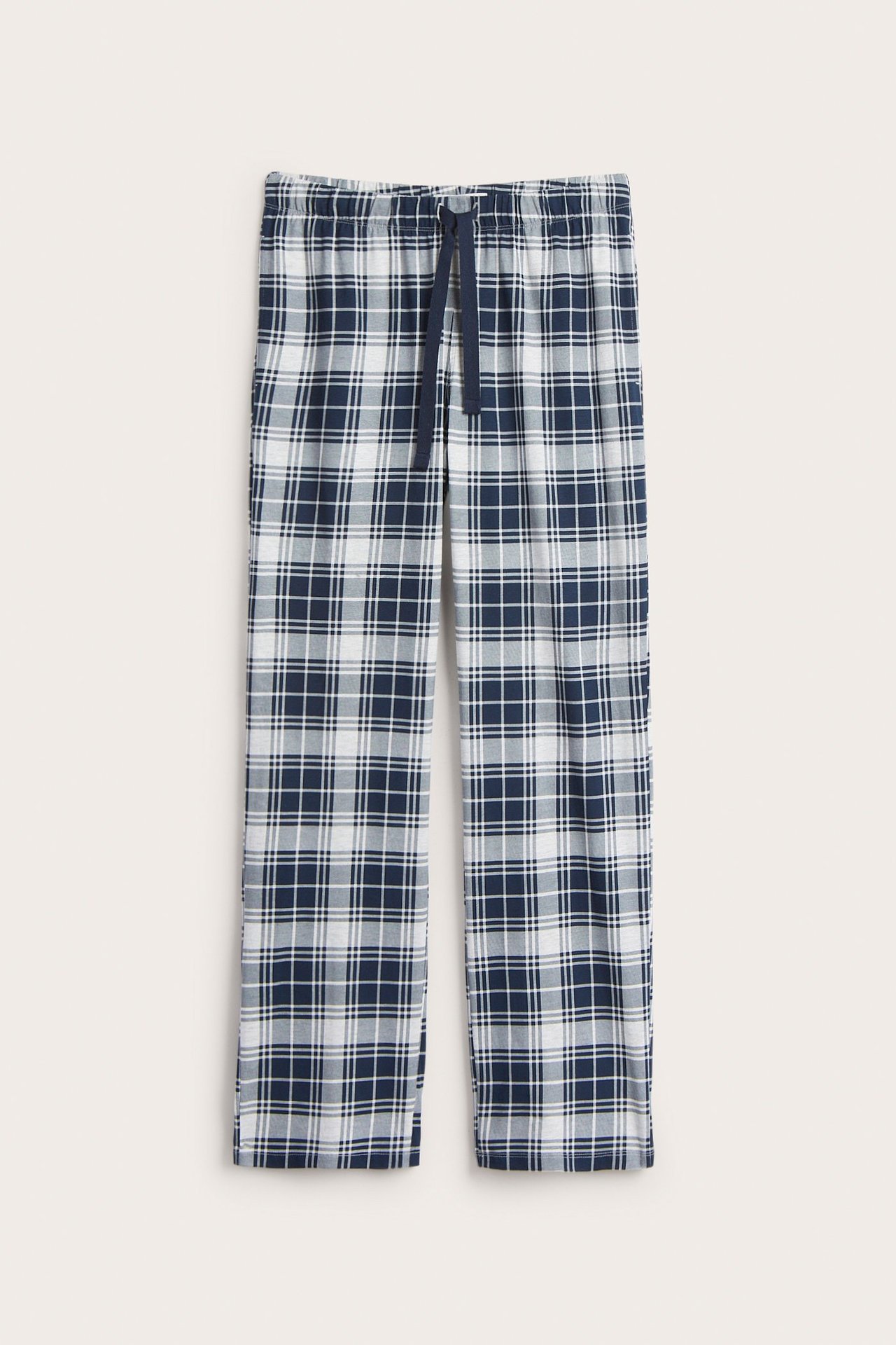 Edestä näkymä miesten tummansinisistä ja valkoisista ruudullisista pyjamahousuista, joustava kiristysnyöri vyötäröllä.