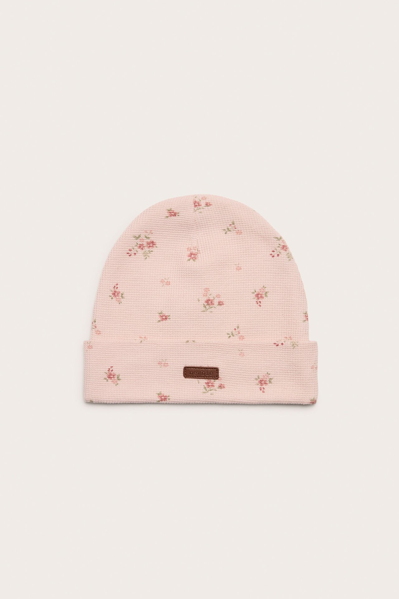 Forfra, lys rosa jerseylue med blomstermønster og oppbrettet kant.