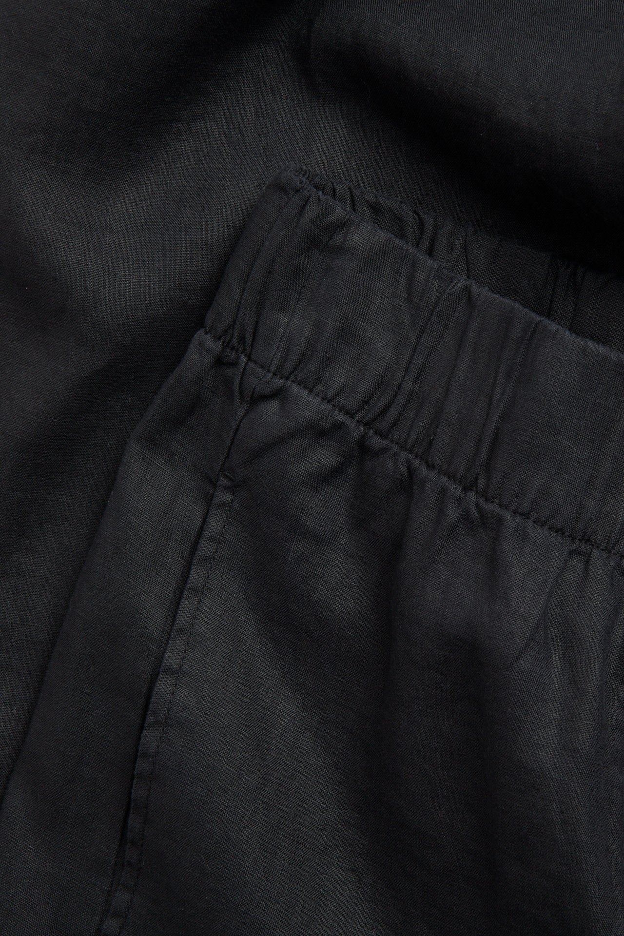 Zbliżenie czarnych lnianych spodni z elastycznym pasem i boczną kieszenią.