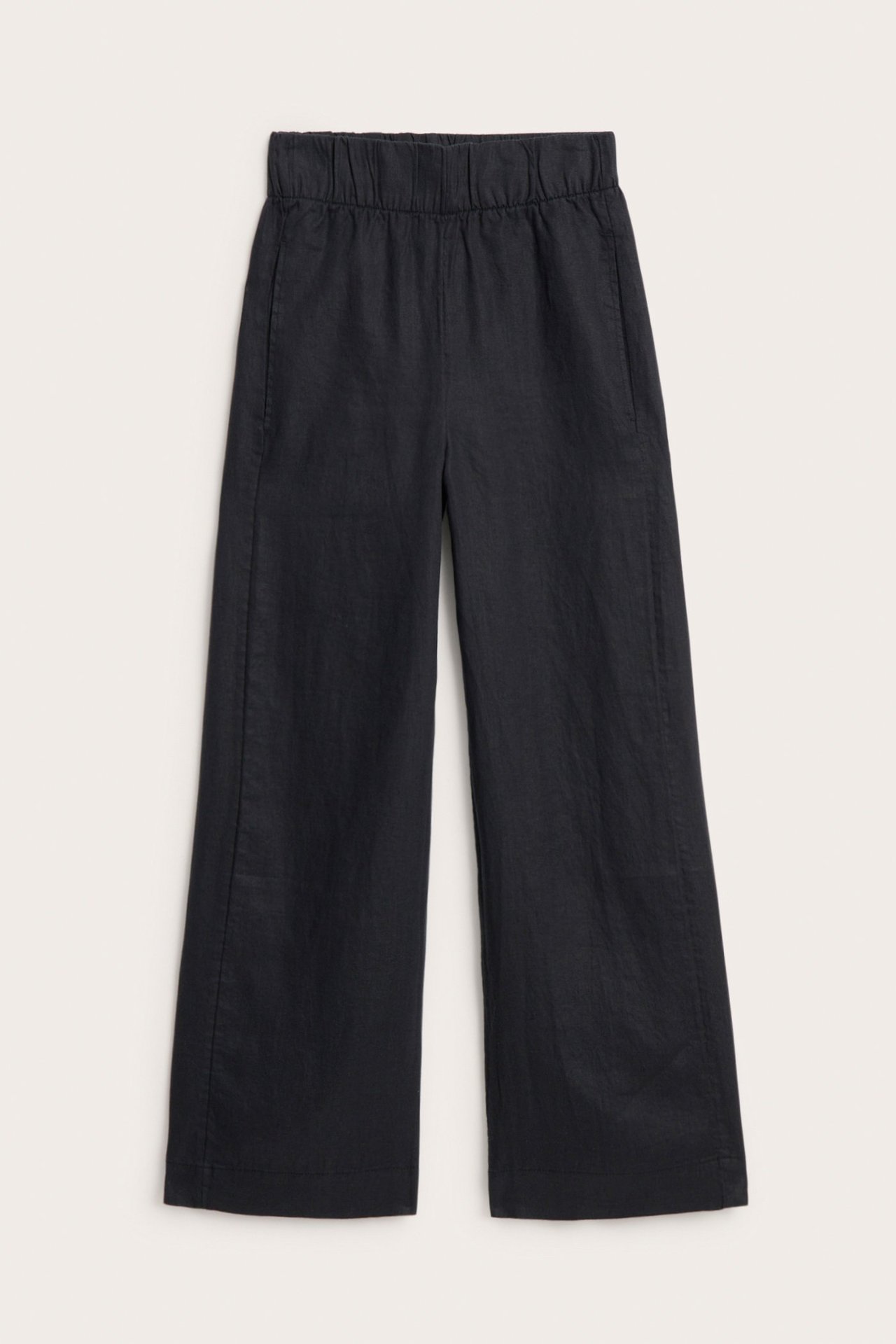 Edestä näkymä mustista pellavahousuista, joissa leveä joustovyötärö, suorat lahkeet ja sivutaskut.