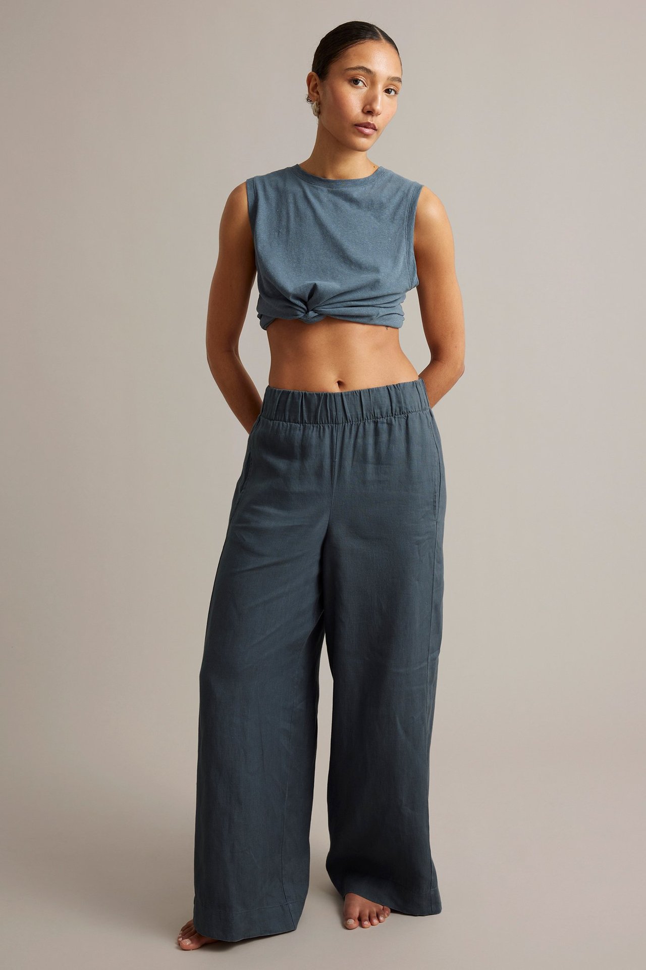 Edestä: Nainen sinisissä leveissä pellavahousuissa, joustovyötäröllä, ja solmitussa crop-topissa.