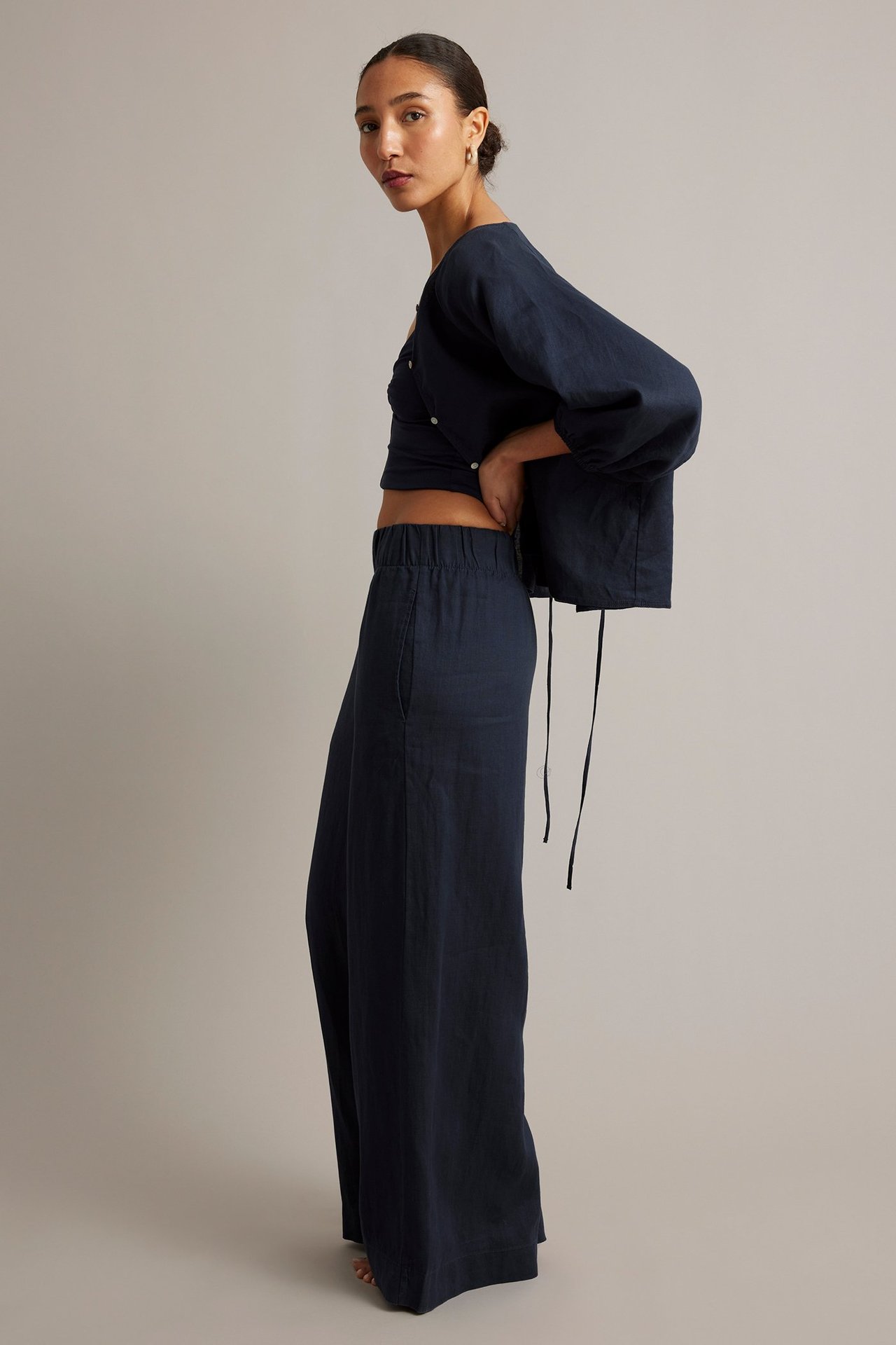 Sivukuva: Tumman siniset pellavaiset leveälahkeiset housut joustovyötäröllä ja taskuilla, plus yhteensopiva toppi.