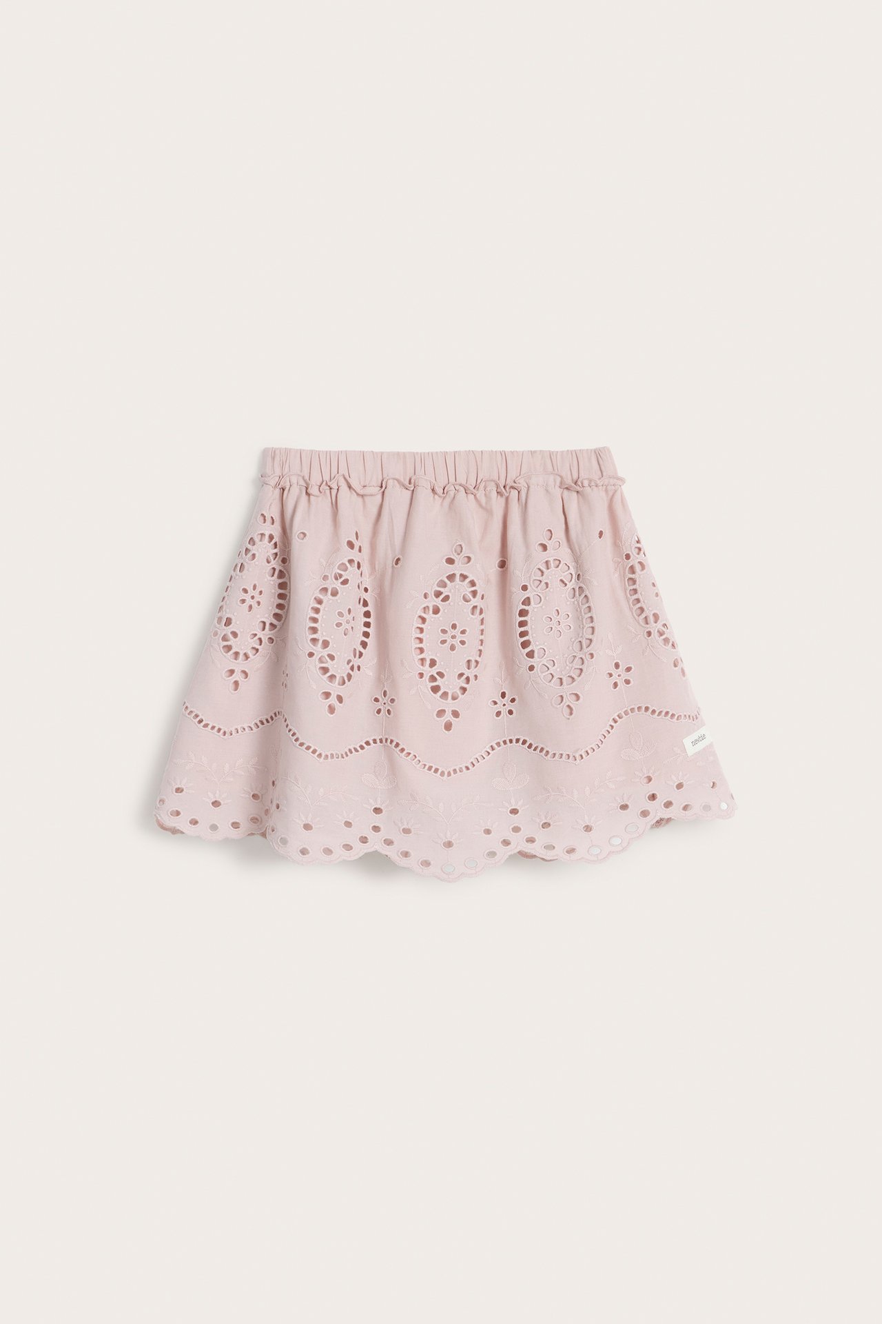 Frontvy av en rosa broderad bomullskjol för barn med resår i midjan och vågig nederkant.