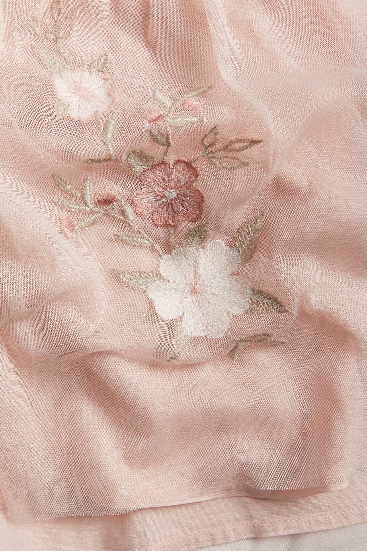 Lähikuva vaaleanpunaisesta verkkomekon kankaasta, jossa on herkkä kukkakirjonta.