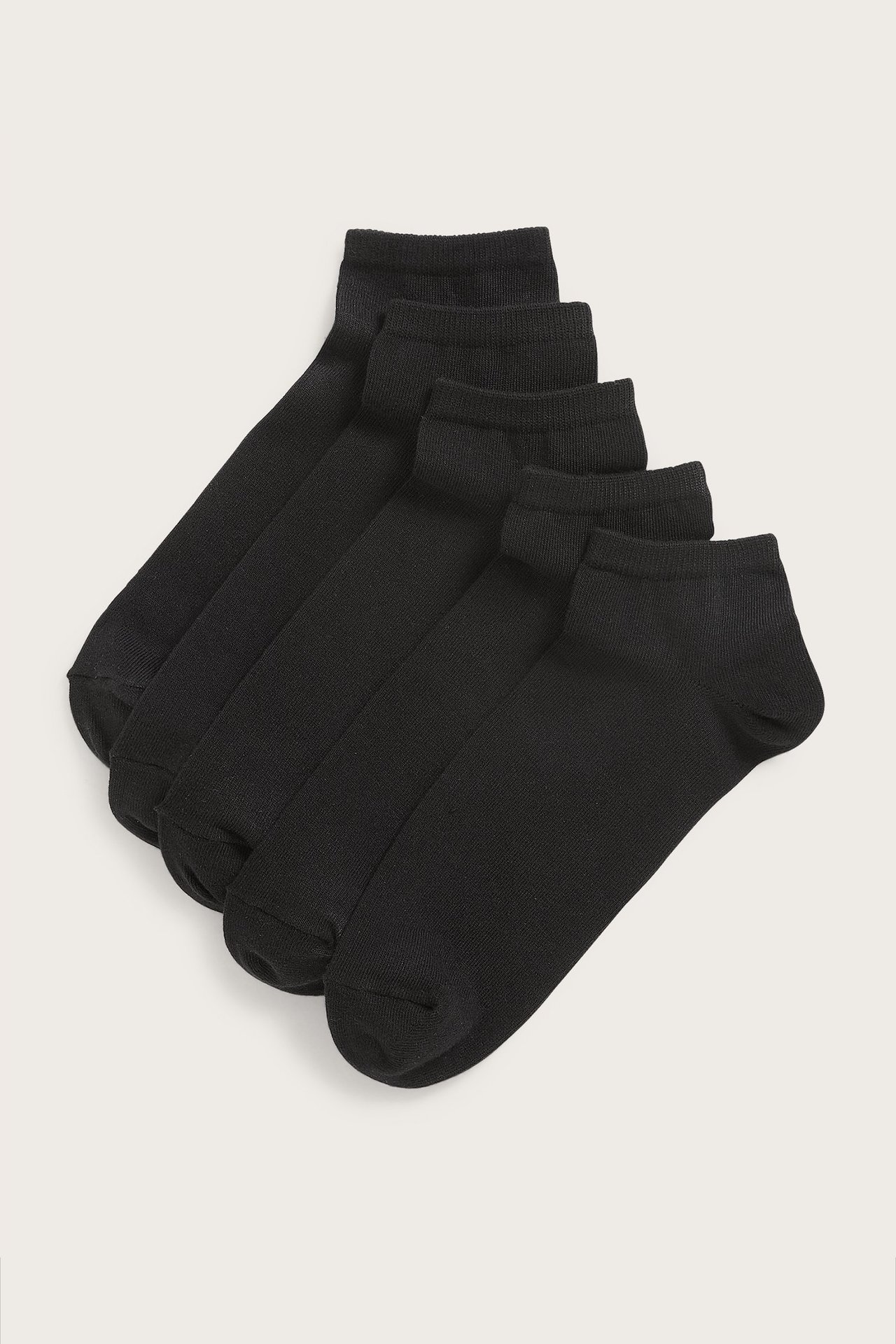 Uppifrån vy av fem par svarta, enfärgade, låga sneakersstrumpor i bomullsmix, prydligt staplade.
