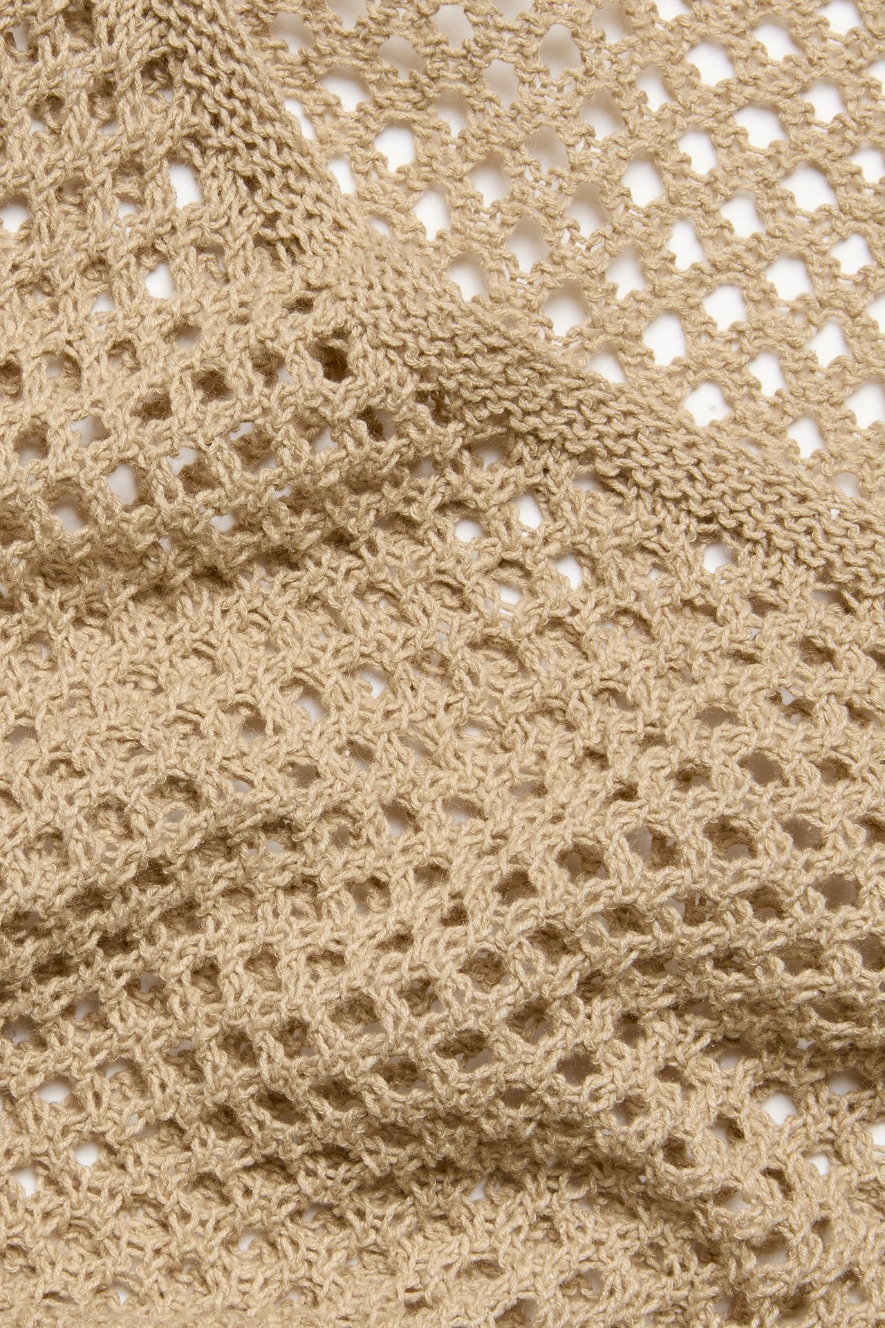 Zbliżenie na ciemnobeżowy, ażurowy materiał sukienki, ukazujący strukturalną tkaninę bawełniano-poliestrową.