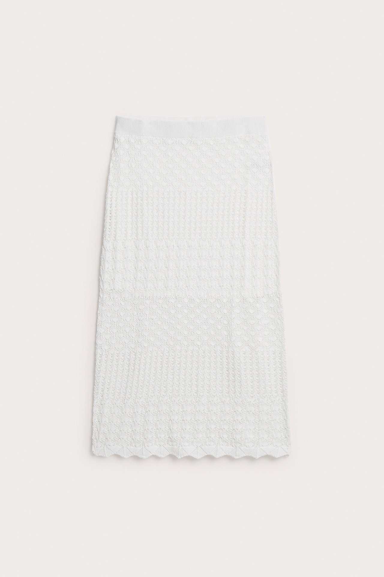 Frontvy av en offwhite stickad jacquardkjol med resår i midjan och vågig nederkant.