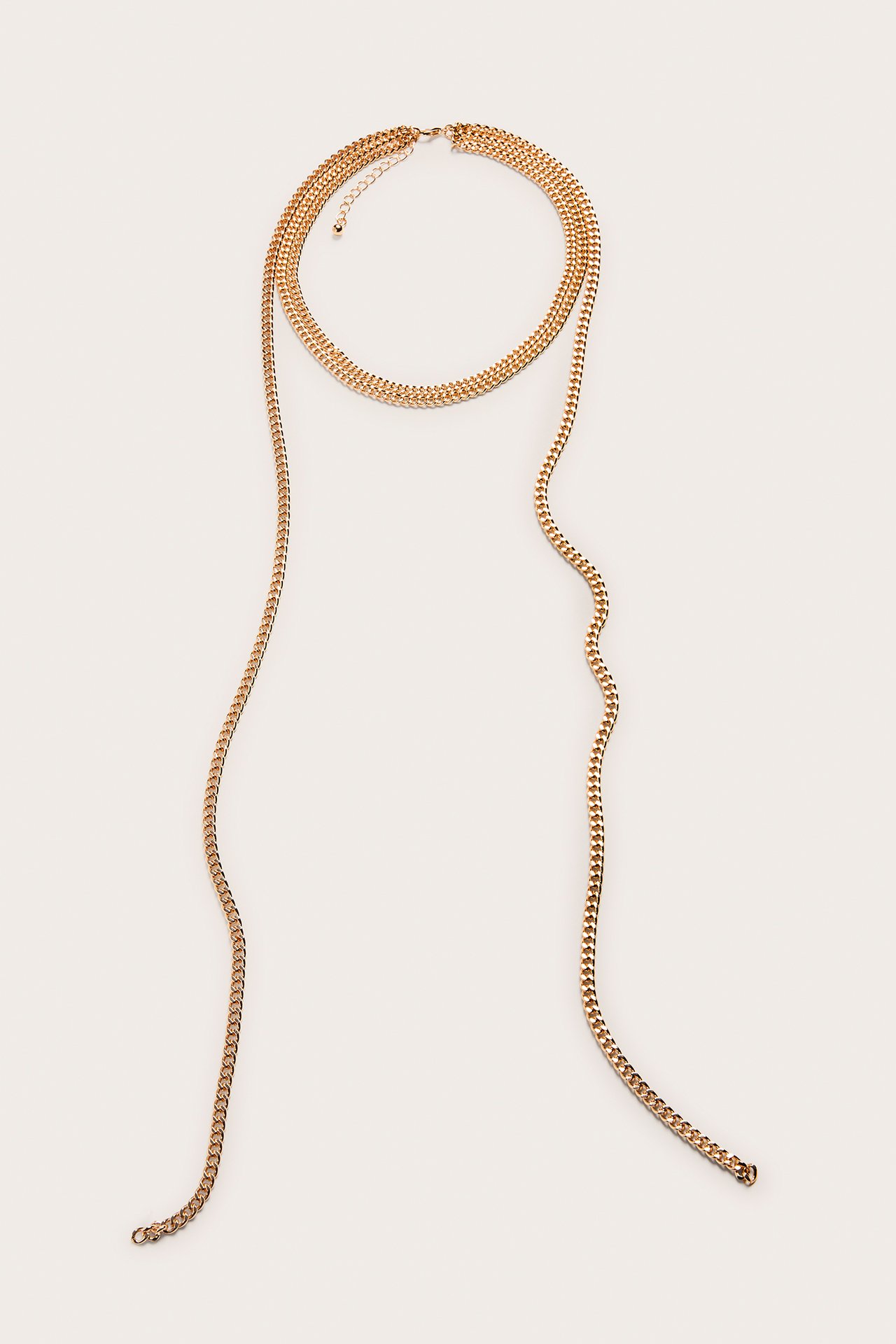 Platt bild av ett guldfärgat lagerhalsband med en kort kedja och två långa, tunna kedjor.