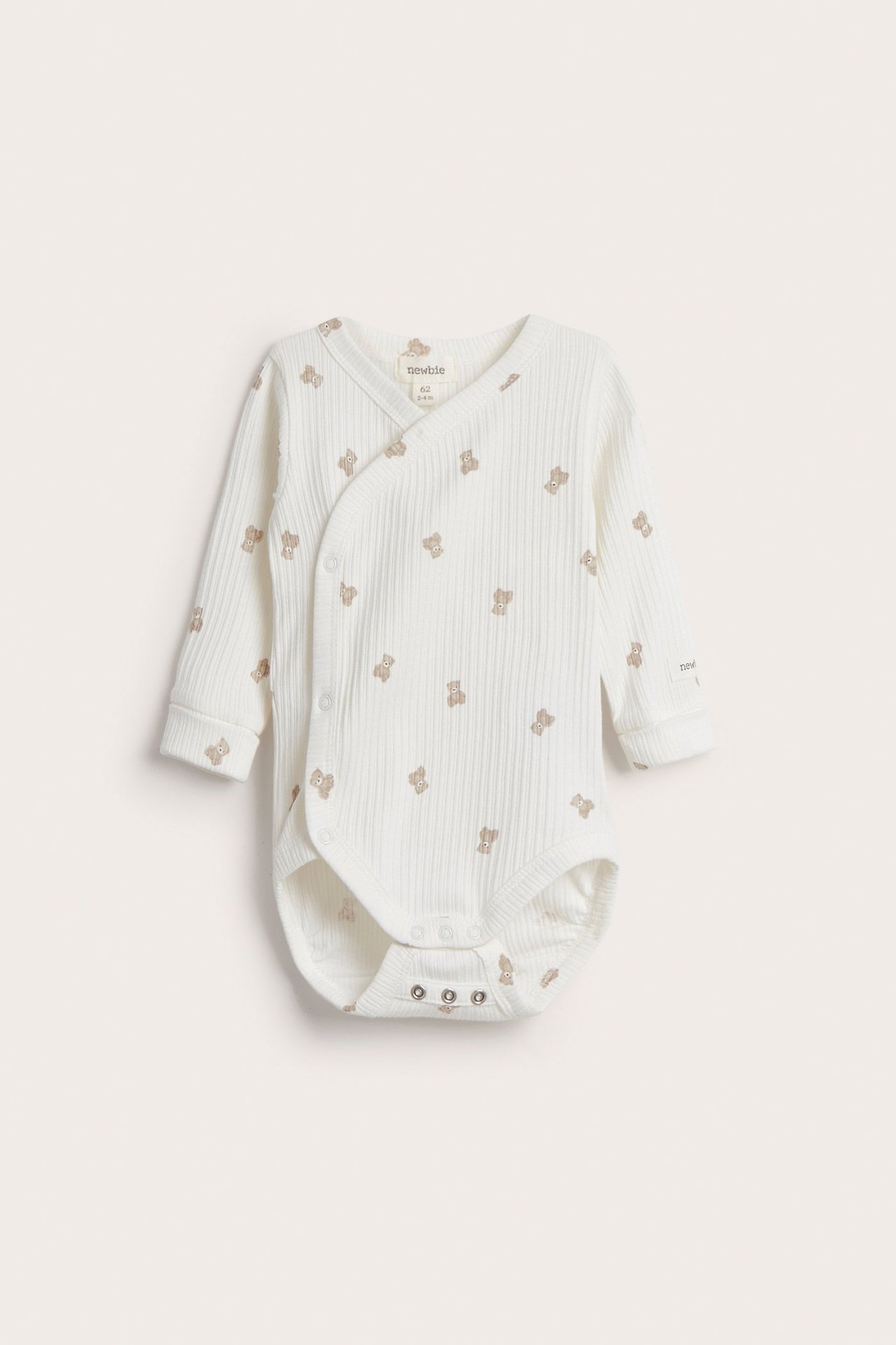 Frontvy av en offwhite ribbad babybody med nallemönster och tryckknappar.