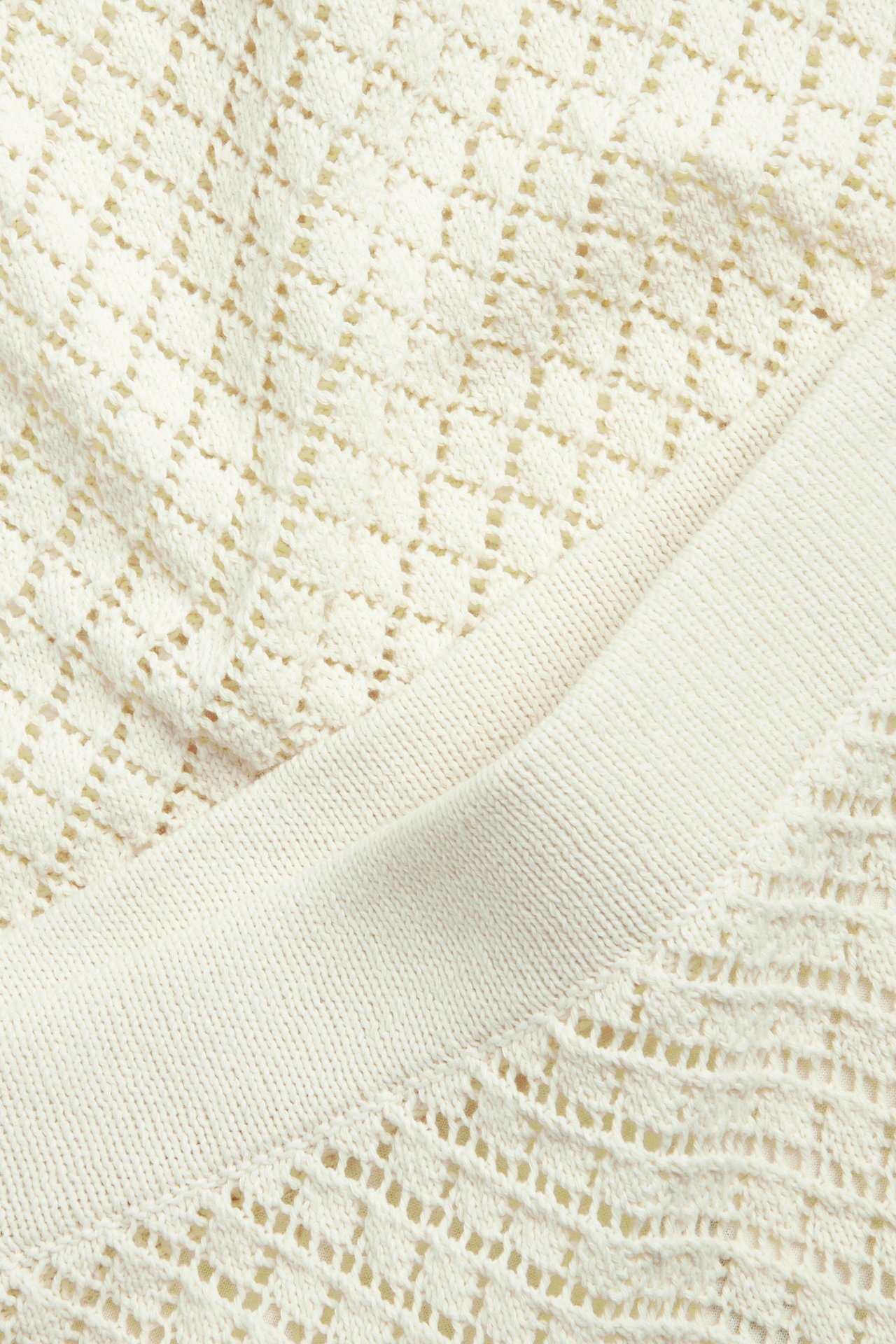 Närbild på en ljusbeige stickad kjol med spetsmönster och ribbad kant.