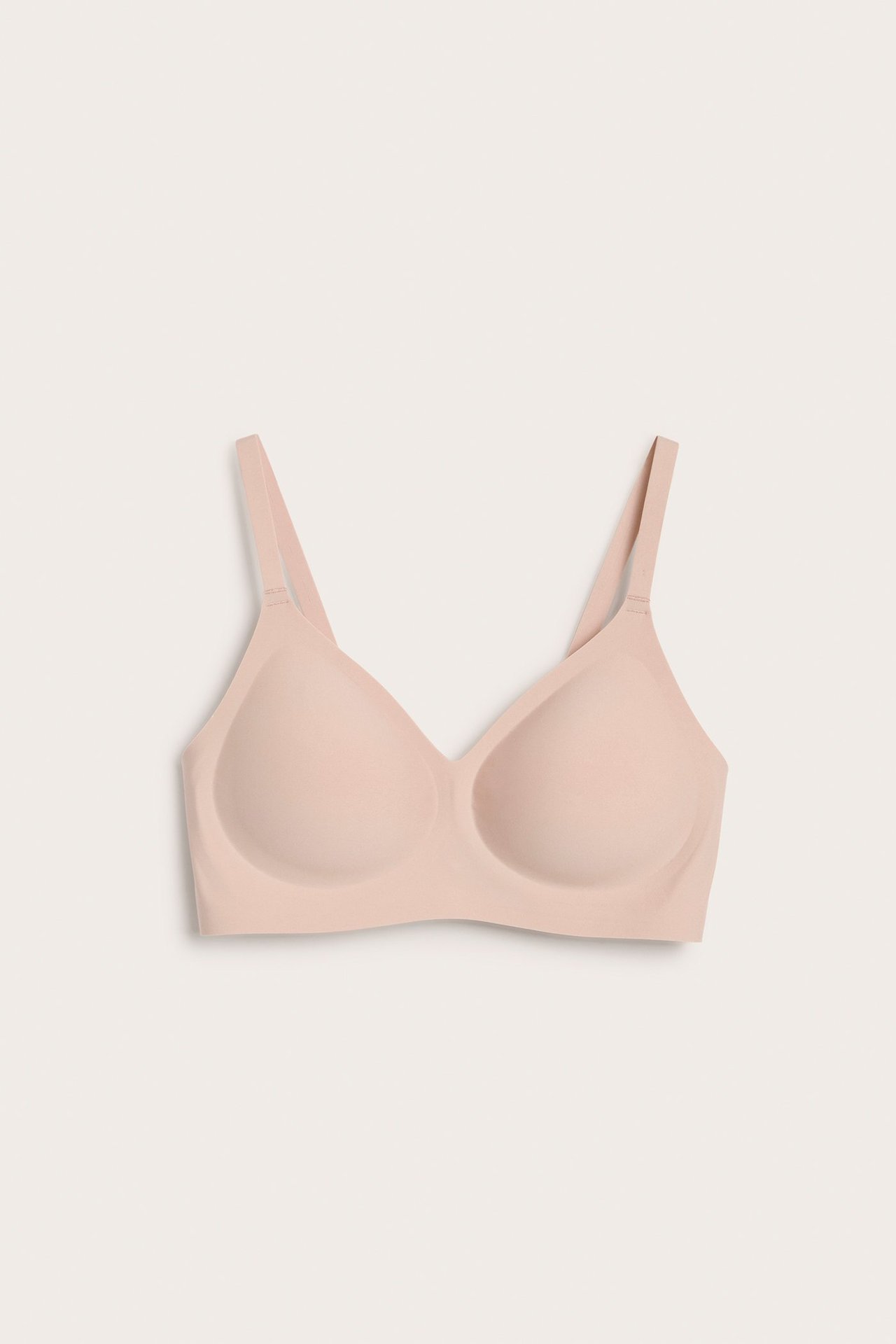 Frontvisning av en lys rosa bøylefri BH i supermykt, sømløst mikrostoff med justerbare stropper.