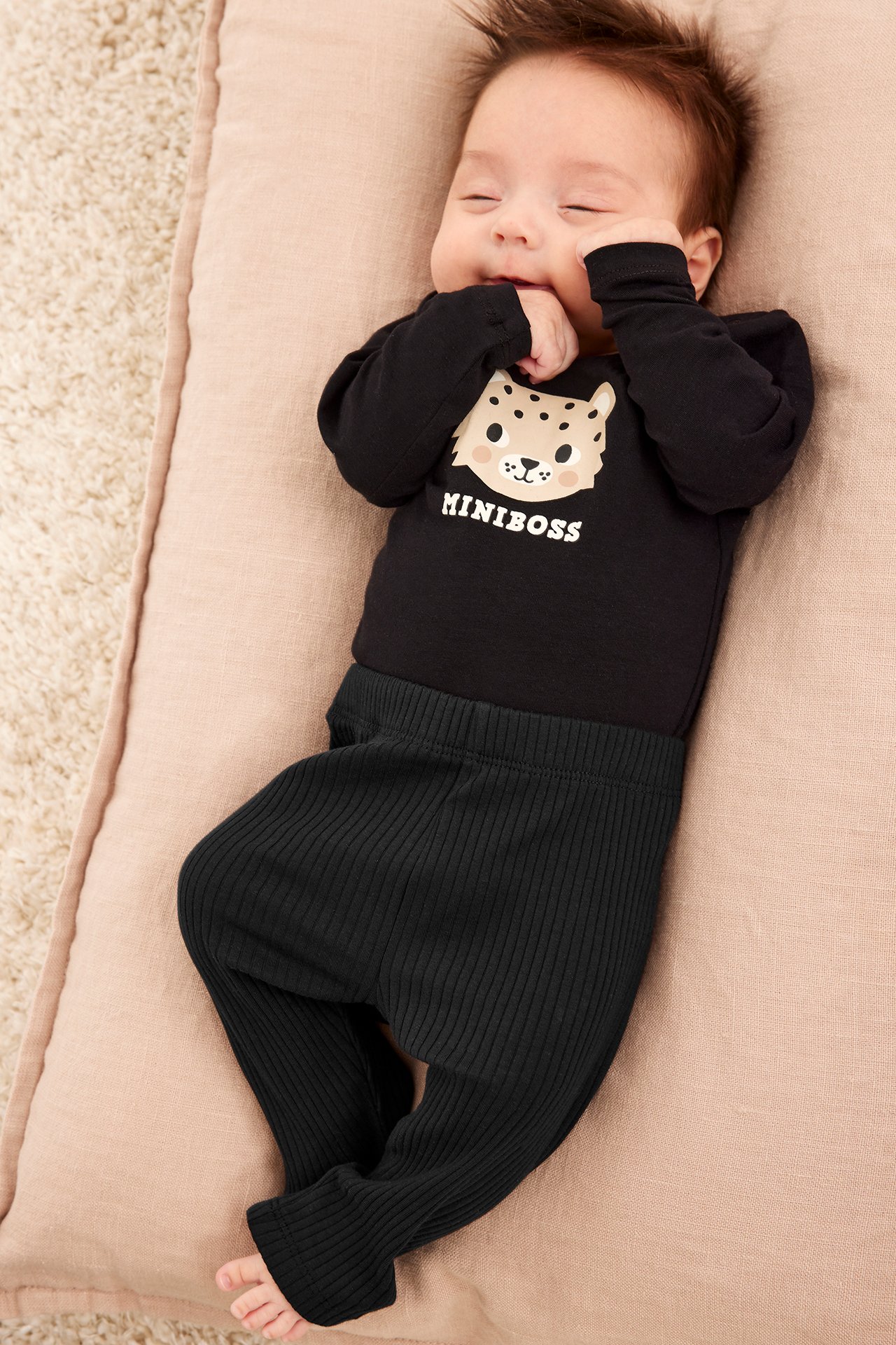 Uppifrån, baby i svarta ribbade leggings och svart långärmad body med leopardtryck.