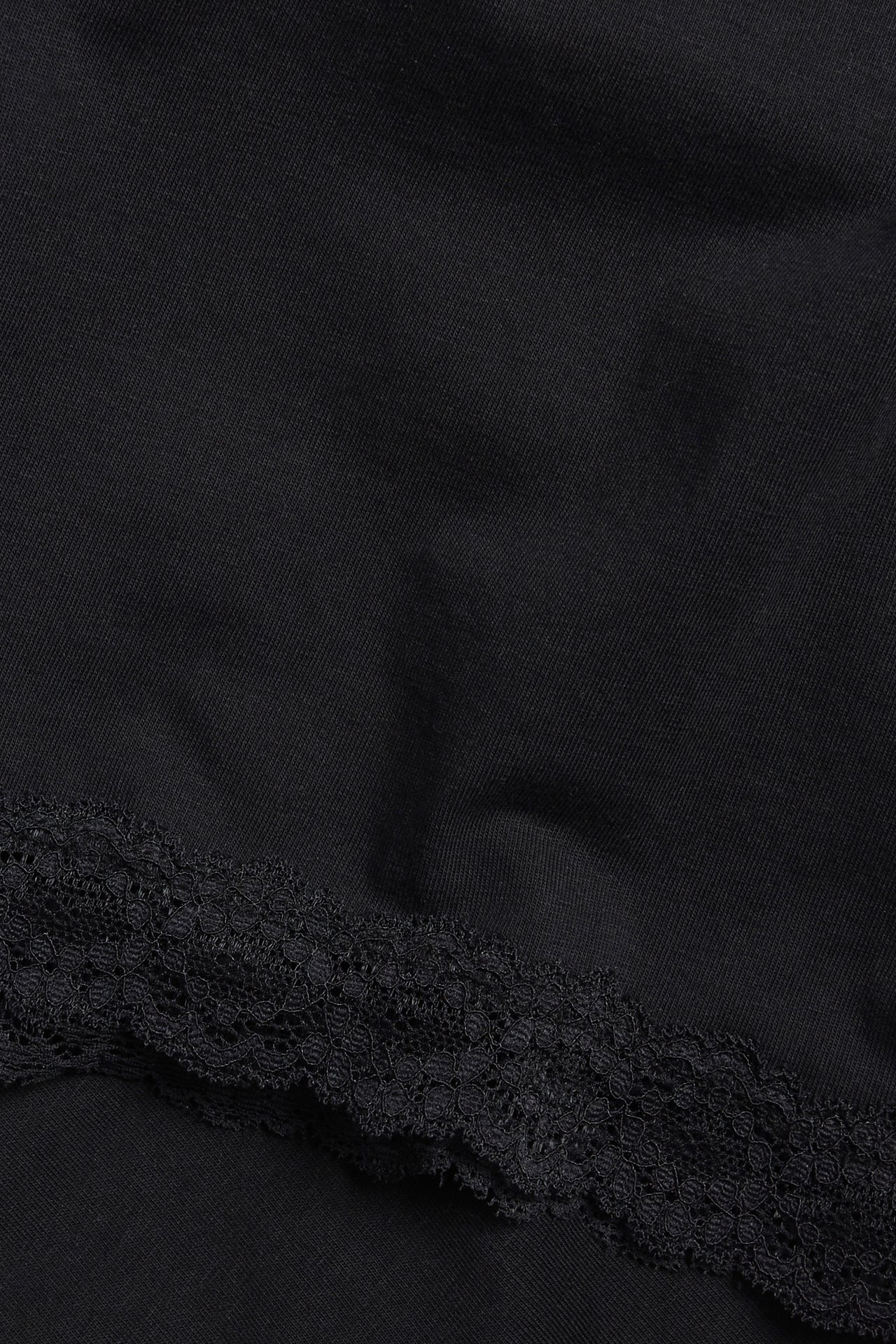 Närbild av svarta mjuka shorts med en delikat spetskant.