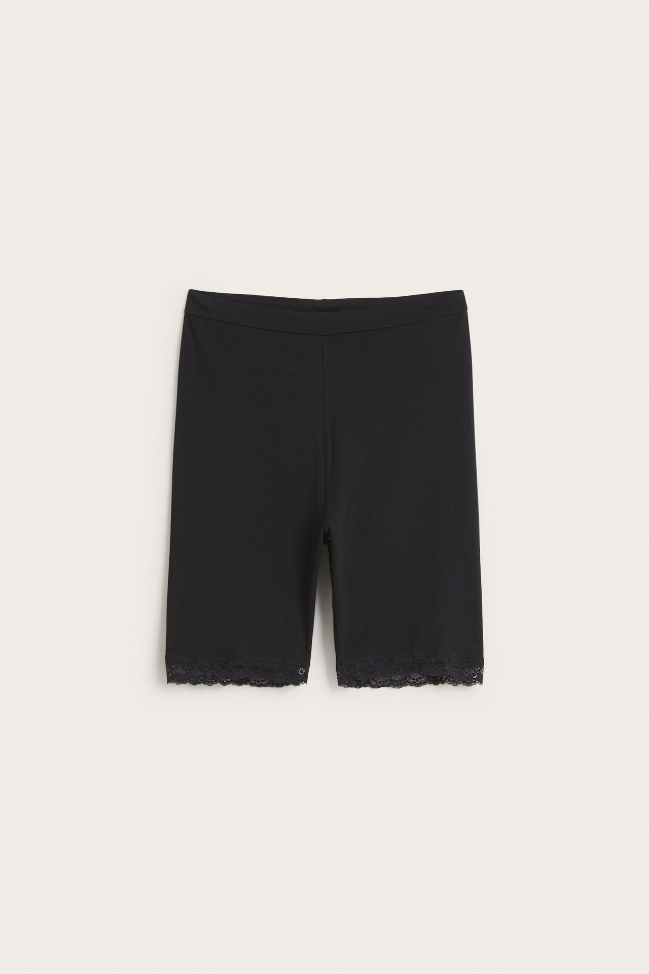 Frontvy av svarta bomullsshorts med resår i midjan och delikat spetskant vid benöppningarna.