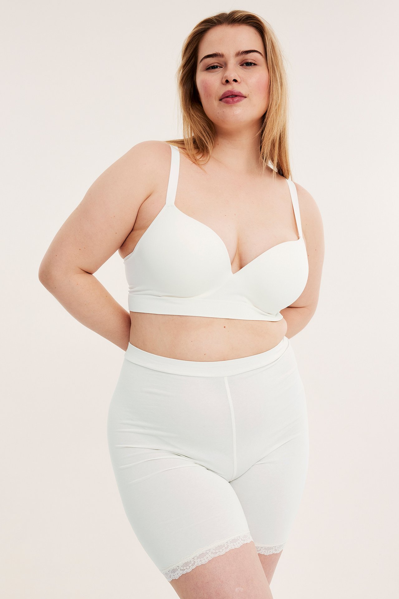 Framifrån, kvinna i offwhite bomullsshorts med spetskant och matchande offwhite behå.