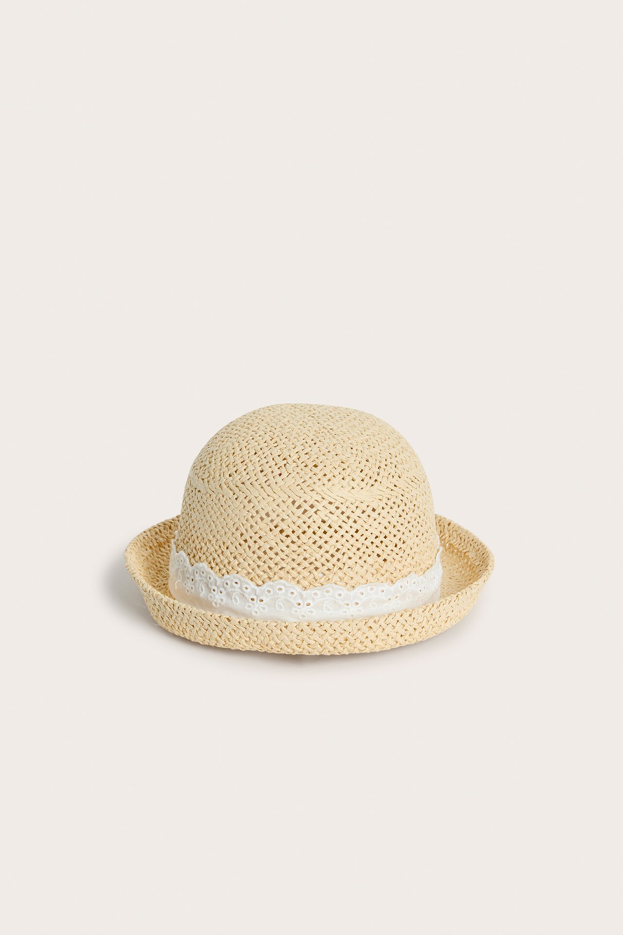 Forfra, lys beige stråhatt for barn med et hvitt blondebånd rundt pullen.