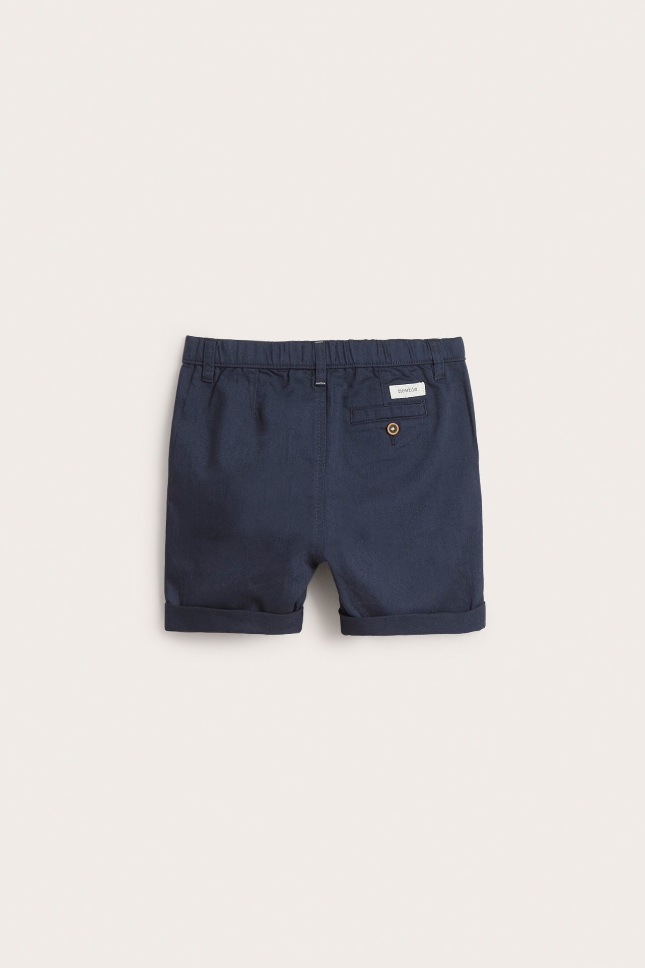 Widok z tyłu granatowych tkanych bawełnianych szortów dziecięcych z elastyczną talią, kieszenią i podwiniętymi nogawkami.