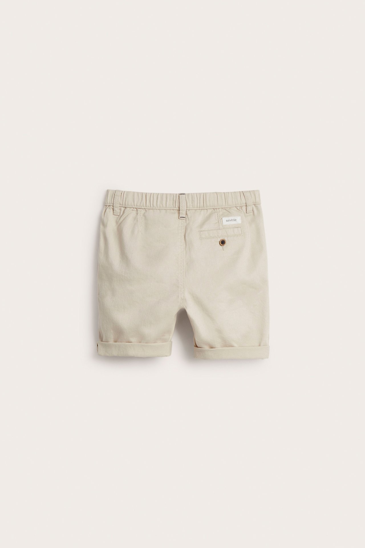 Bakfra: beige vevde bomullsshorts for barn med elastisk midje, baklomme og oppbrettede benkanter.