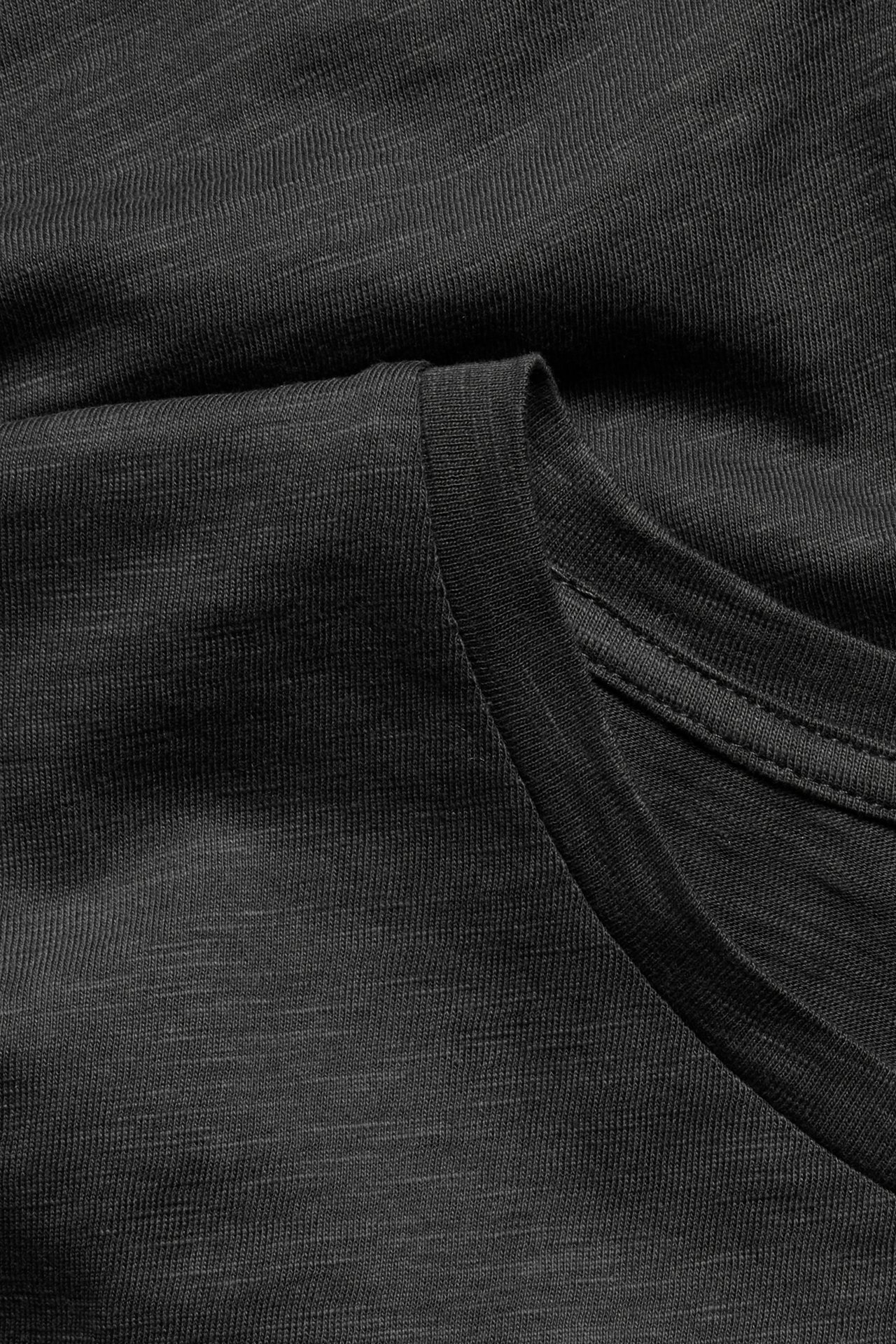 Zbliżenie na czarny, cienki bawełniany T-shirt typu slub z okrągłym dekoltem.