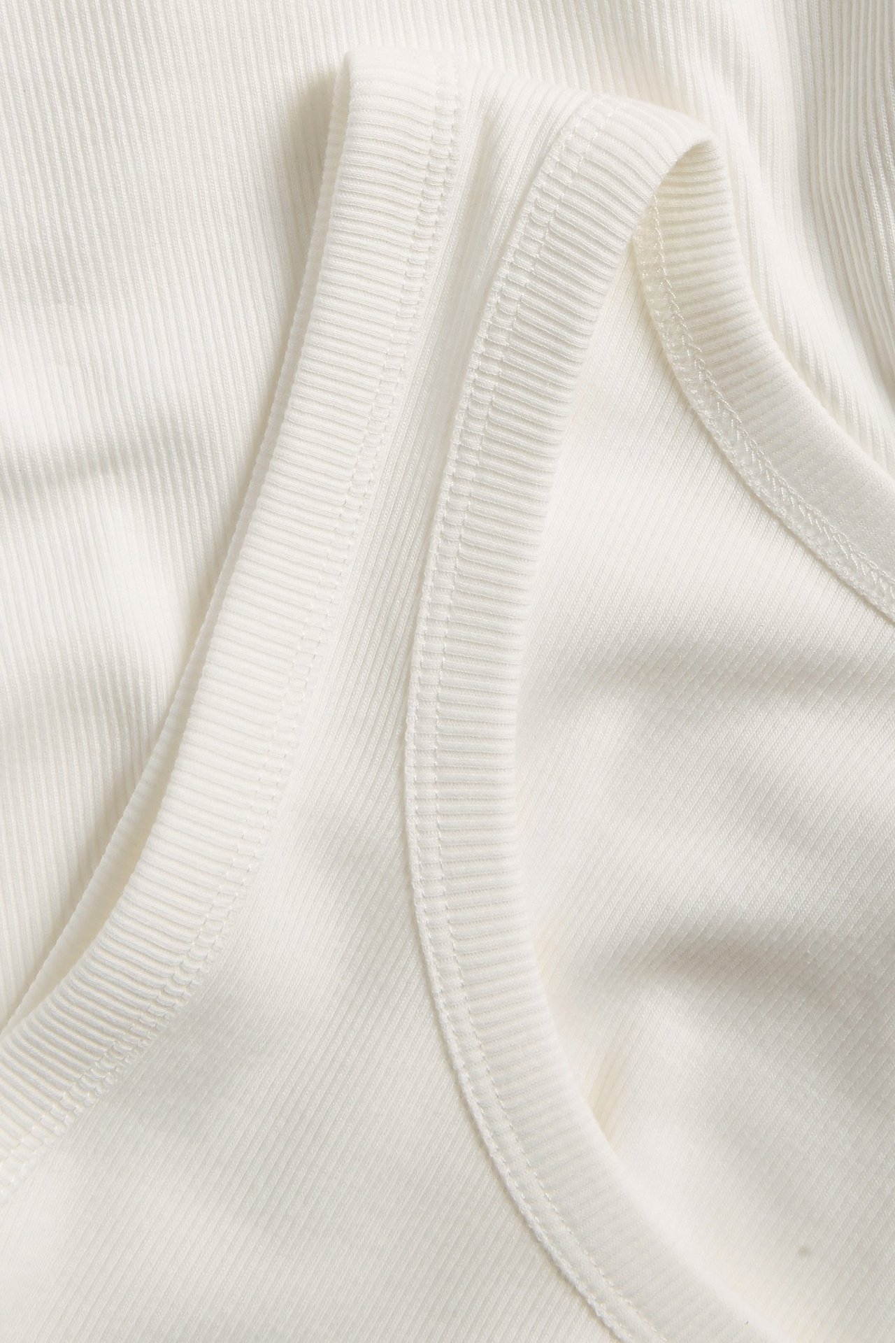 Närbild av ett offwhite ribbat linne med smal struktur och fin ribbad kant.