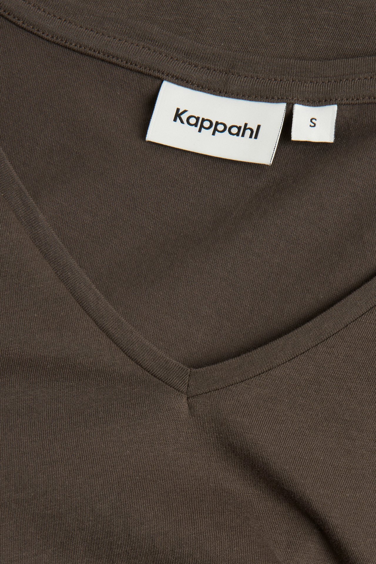 Nærbilde av en mørkebrun V-hals t-skjorte i tynn bomull, med hvit Kappahl-etikett.