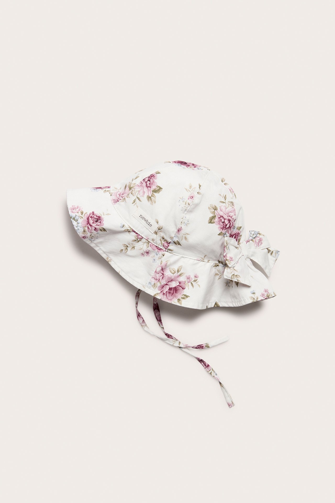 Ovenfra: Offwhite blomstret bomullssolhatt for baby/barn med sløyfe bak og knytebånd.