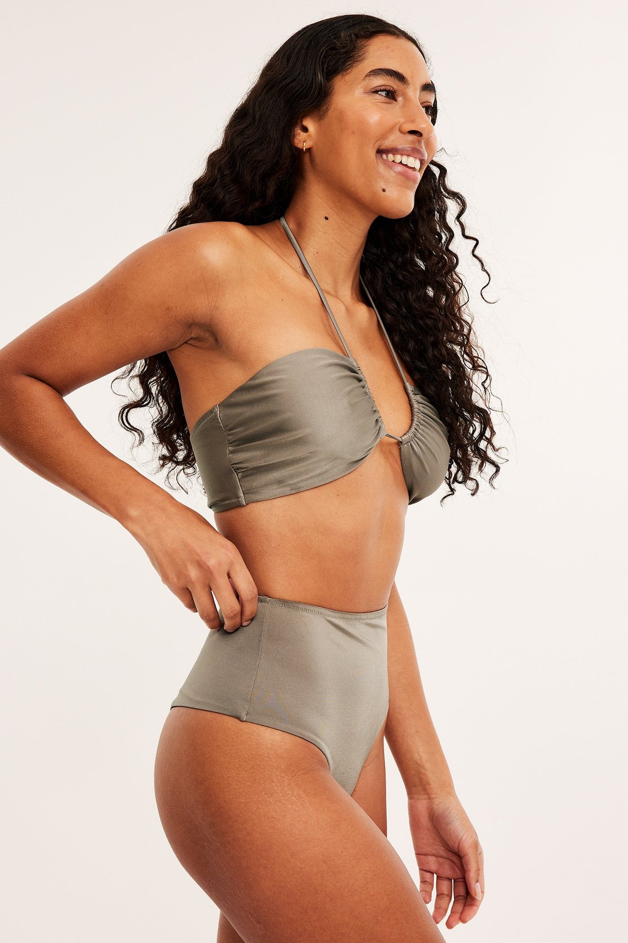 Sidovy: kvinna i enfärgade mörkbeigea högmidjade cheeky bikinitrosor och matchande rynkad bandeau-bikinitopp.