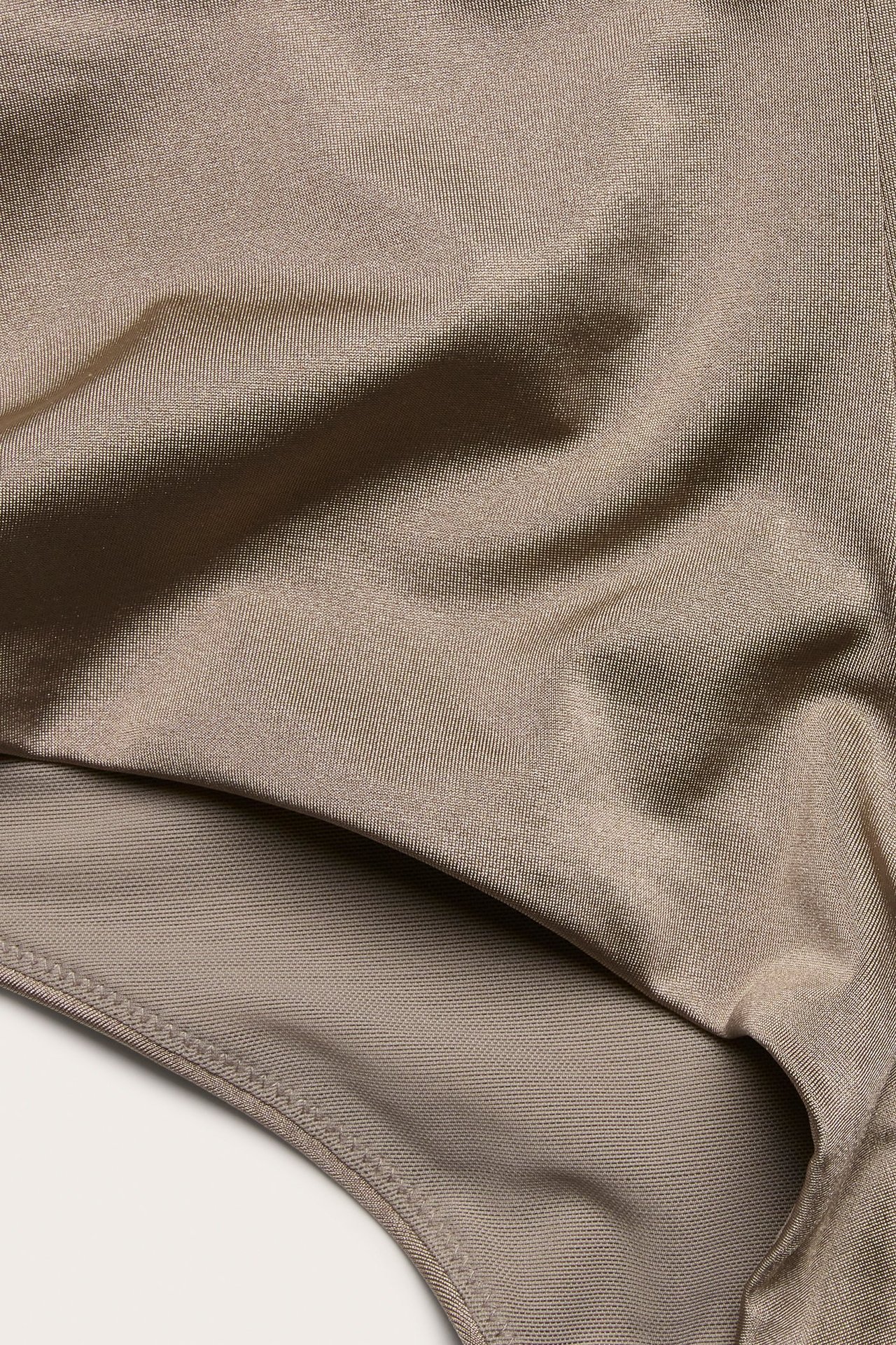 Zbliżenie na ciemnobeżowy, jednobarwny materiał fig bikini z wysokim stanem.