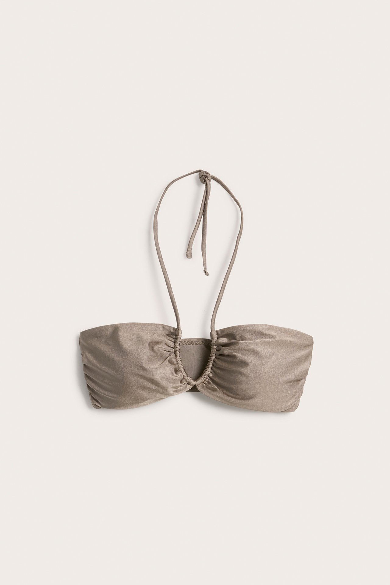 Framifrån, mörkbeige glansig bandeau bikiniöverdel med knytband i nacken och rynkade detaljer.