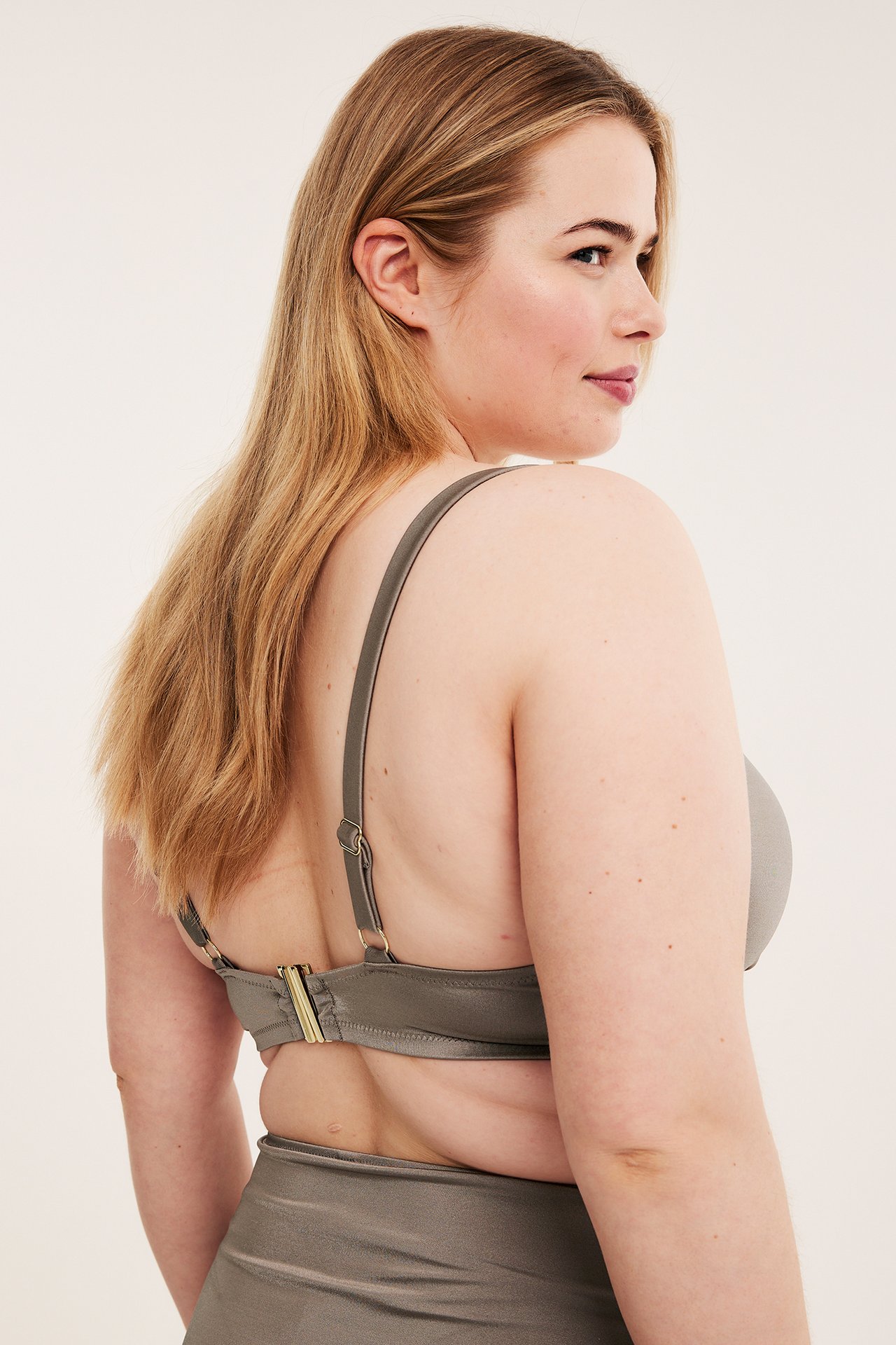 Rygg-sidovy av en kvinna i mörkbeige enfärgad bikini-bh med justerbara band och matchande bikinitrosa.