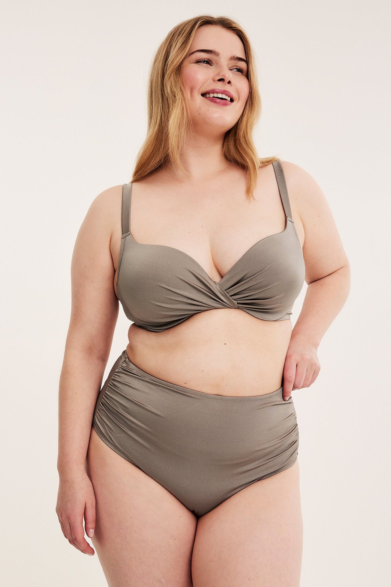 Forfra: kvinne i mørk beige polstret bikinitopp med vridd front og matchende høy midje truse.