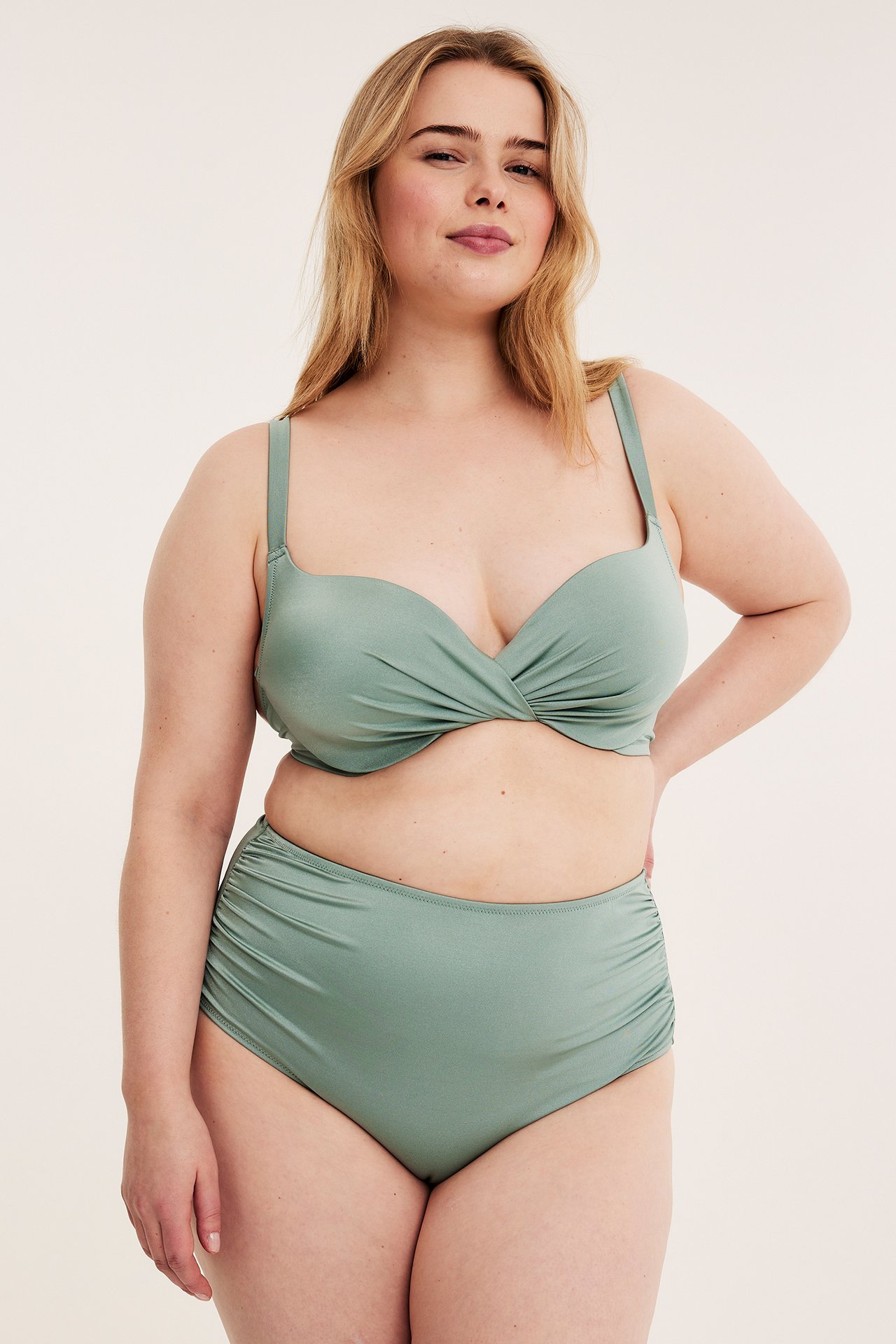 Framifrån: kvinna i ljusgrön vadderad bikini-bh med omlott fram och matchande hög midja bikinitrosor.