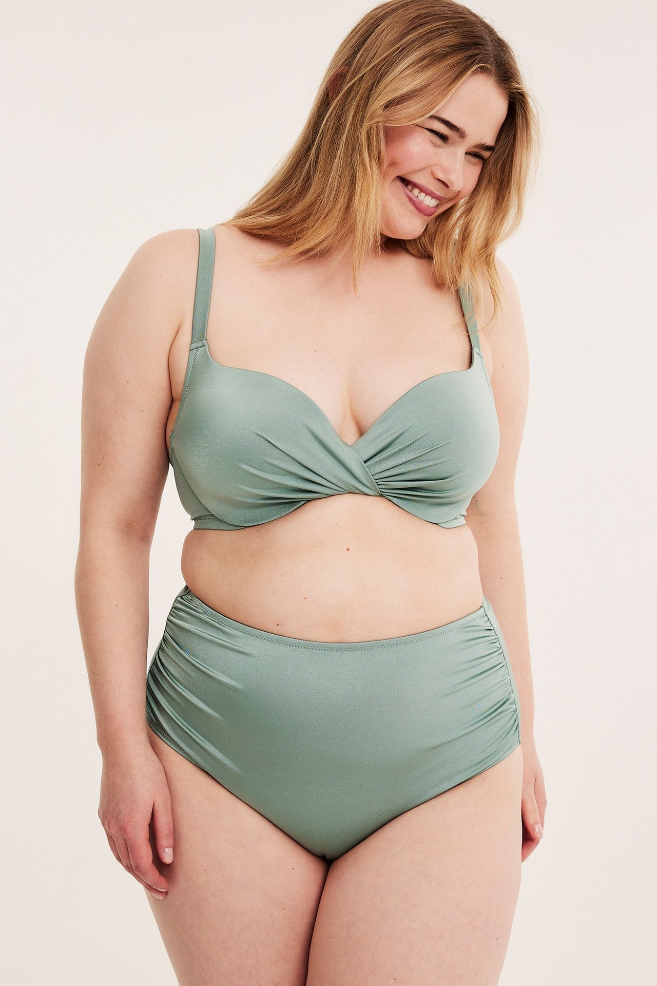 Forfra, kvinne i lysegrønn høy bikinitruse med rynker i siden og matchende vridd bikinitopp.